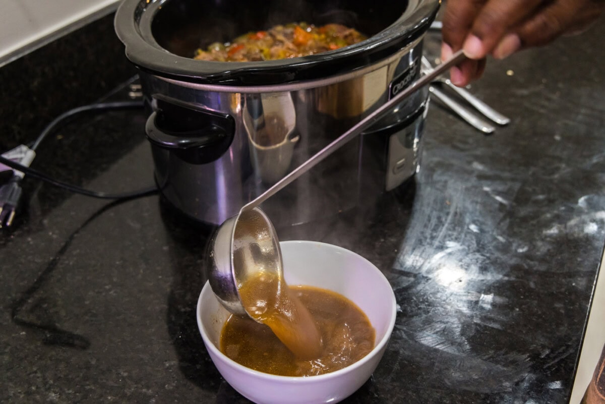 spooning excess liquid from beef carnitas