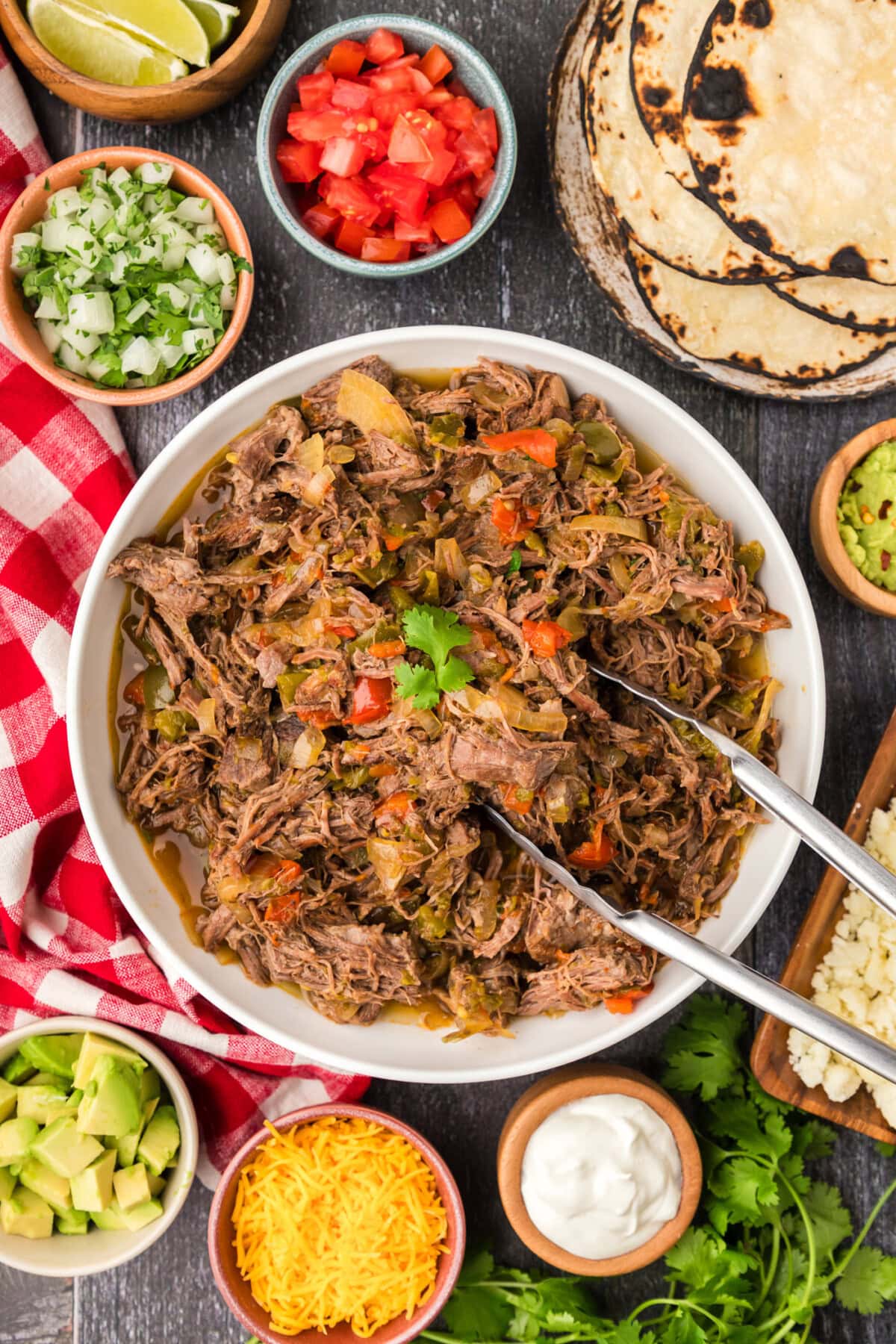Tongs in a bowl of Beef Carnitas
