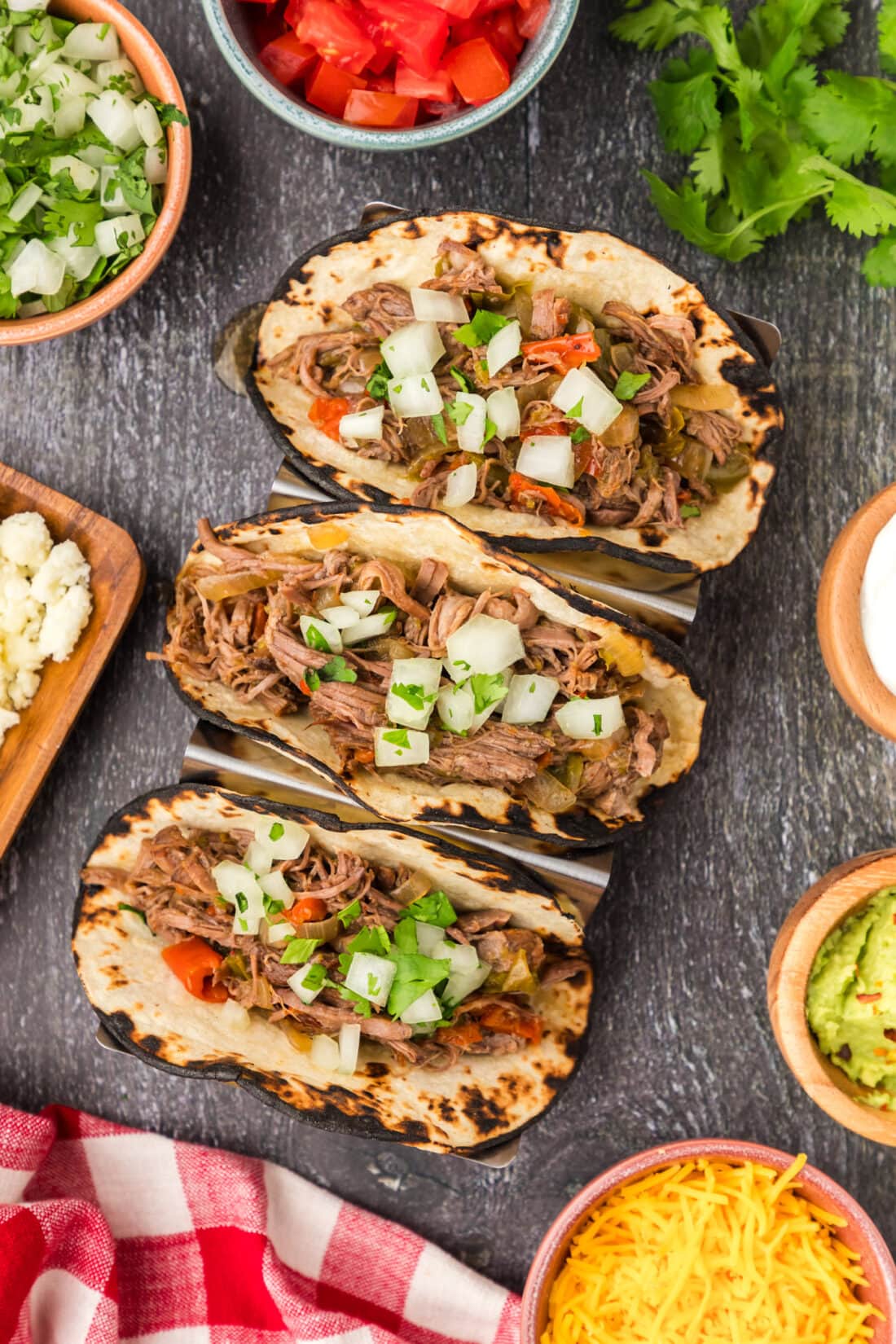 Beef Carnitas resting in tortillas topped with onion and cilantro