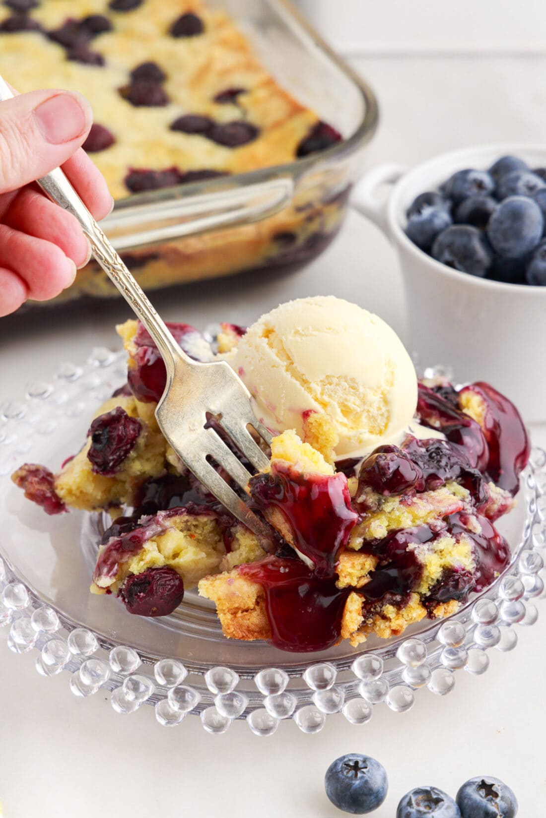 Fork dipping into a serving of Blueberry Dump Cake on a plate