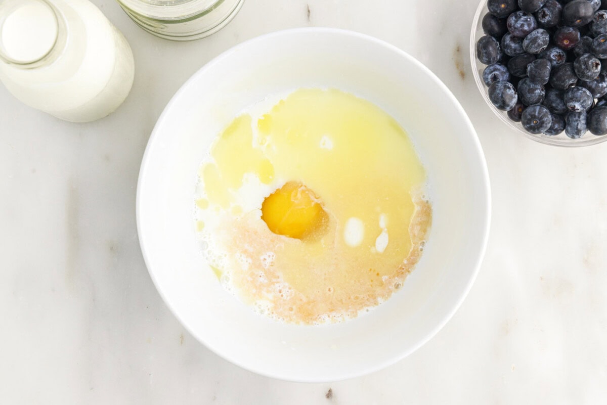 adding eggs, butter, vanilla, and buttermilk to dry ingredients for pancake batter