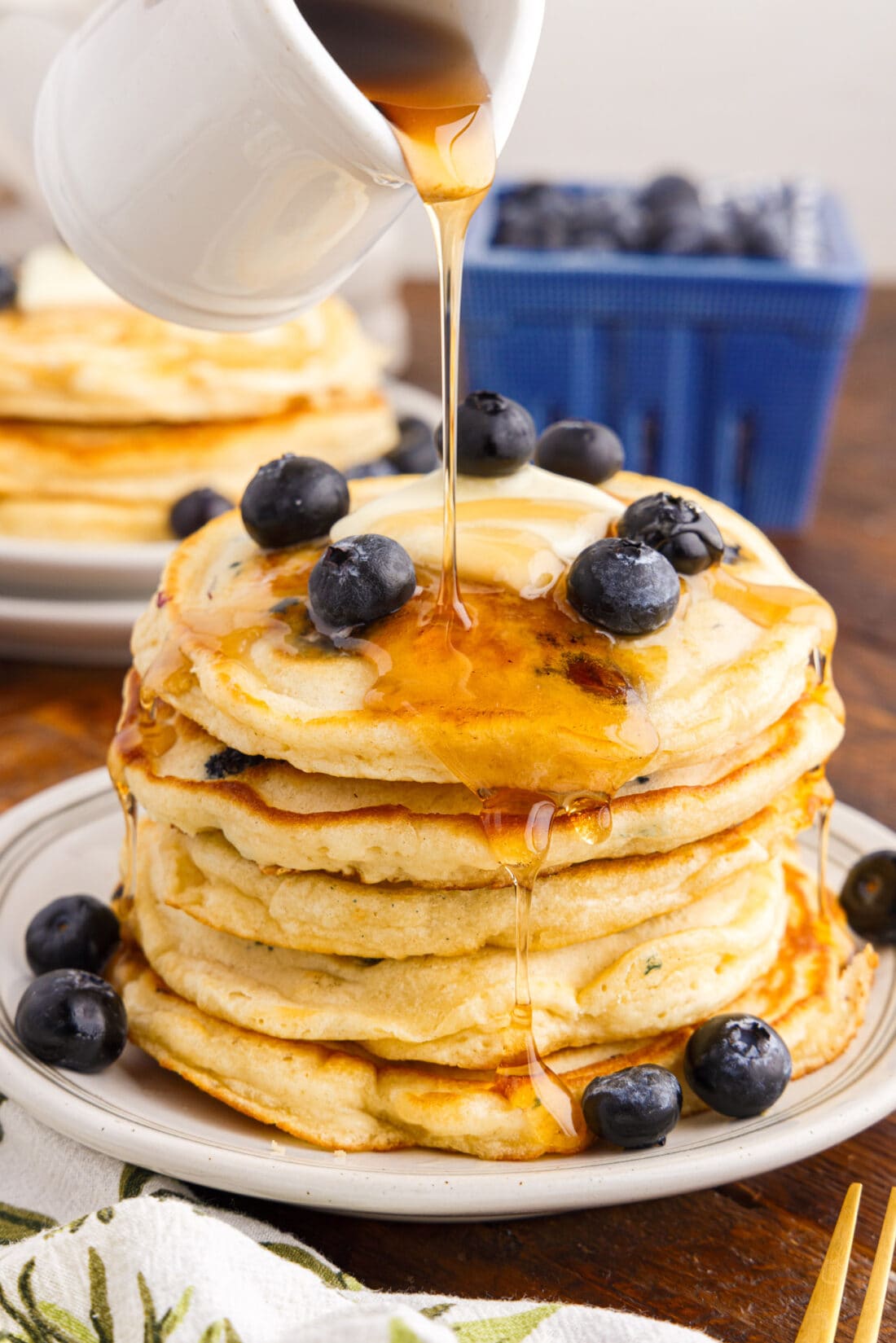 Syrup being poured over a stack of blueberry pancakes
