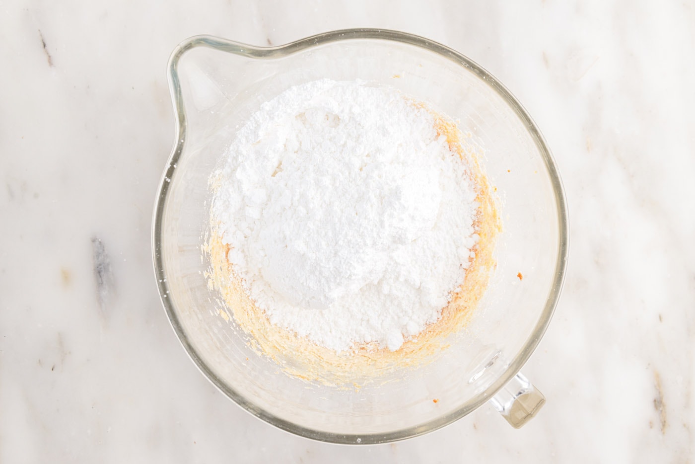 adding powdered sugar to bowl with whipped brown butter
