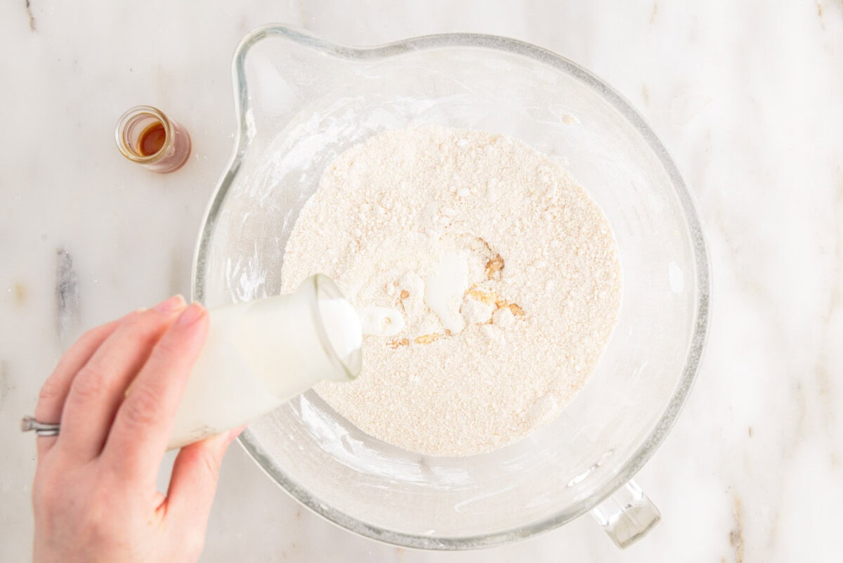 pouring heavy whipping cream to bowl of whipped brown butter and powdered sugar