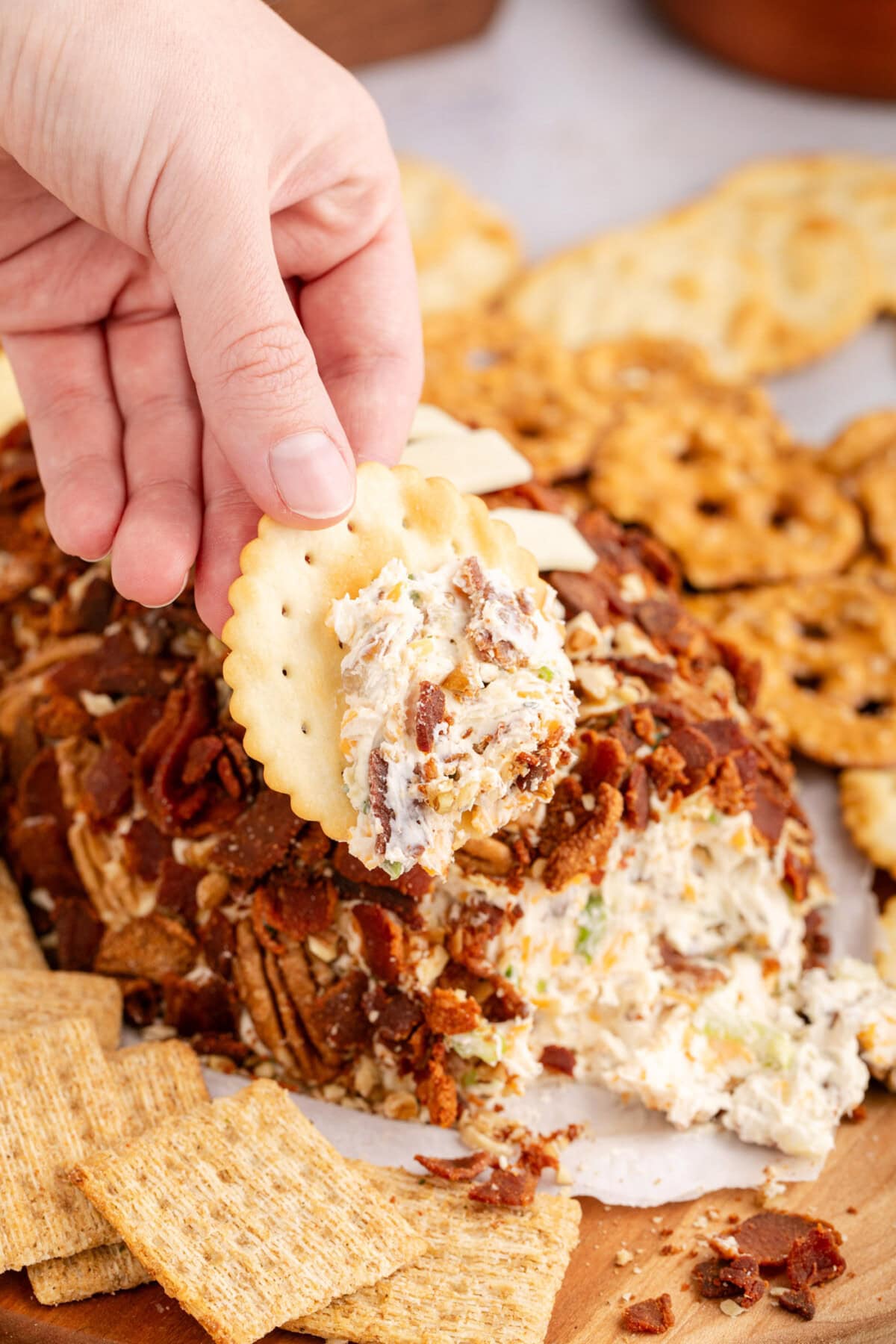 Hand holding a cracker with some cheese on it  from the Football Cheese Ball