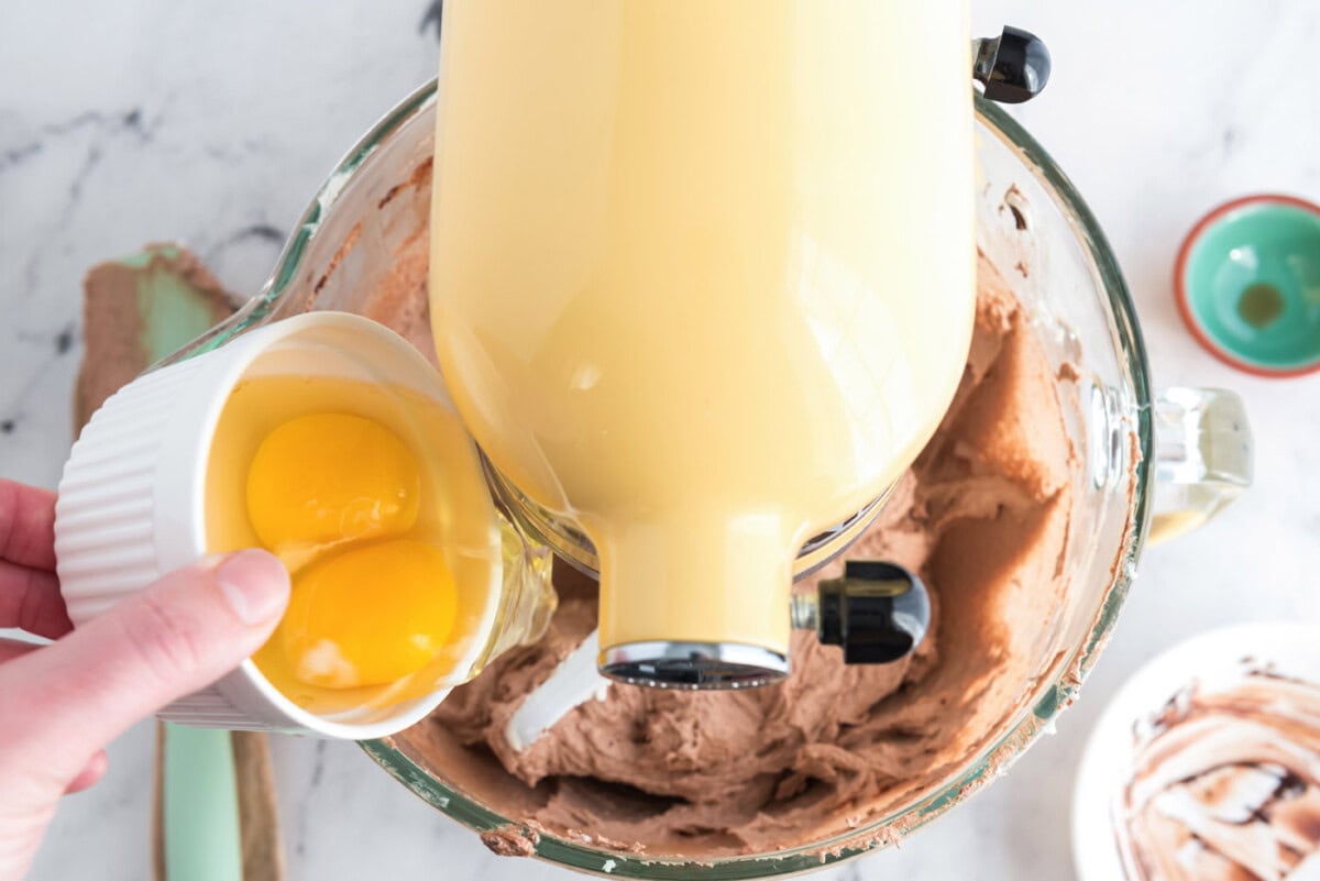 adding eggs to french silk pie in a stand mixer bowl