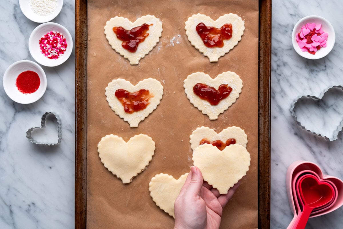 placing pie dough on top of jam filled crust