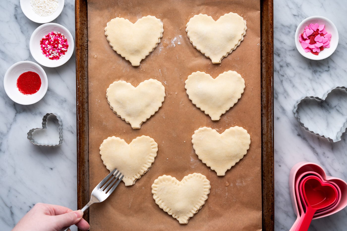 pressing edges of heart shaped pie dough with a fork