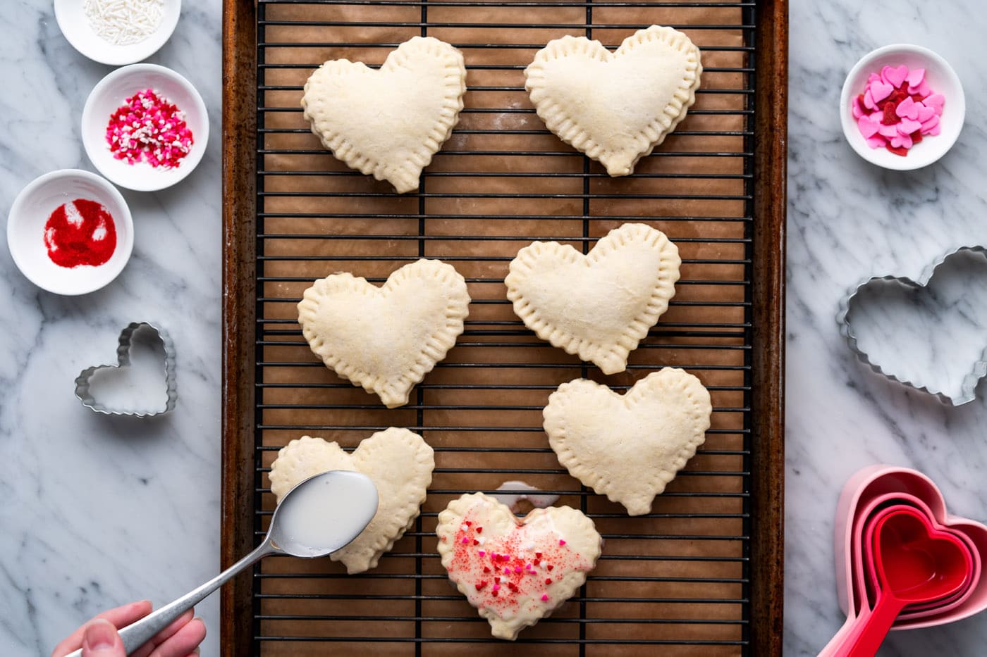 drizzling glaze over heart shaped strawberry pop tarts