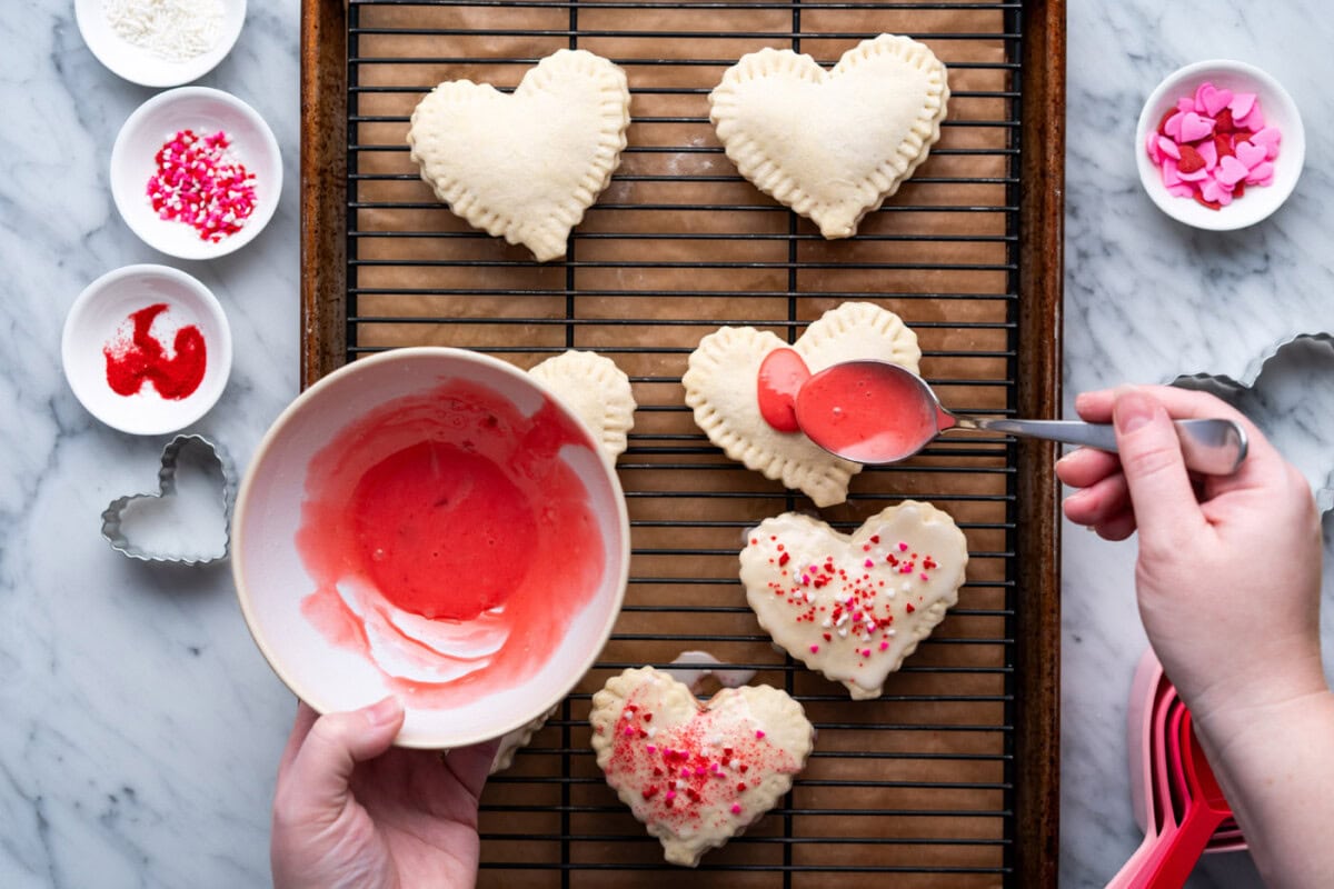 pouring red strawberry glaze over heart shaped pop tarts