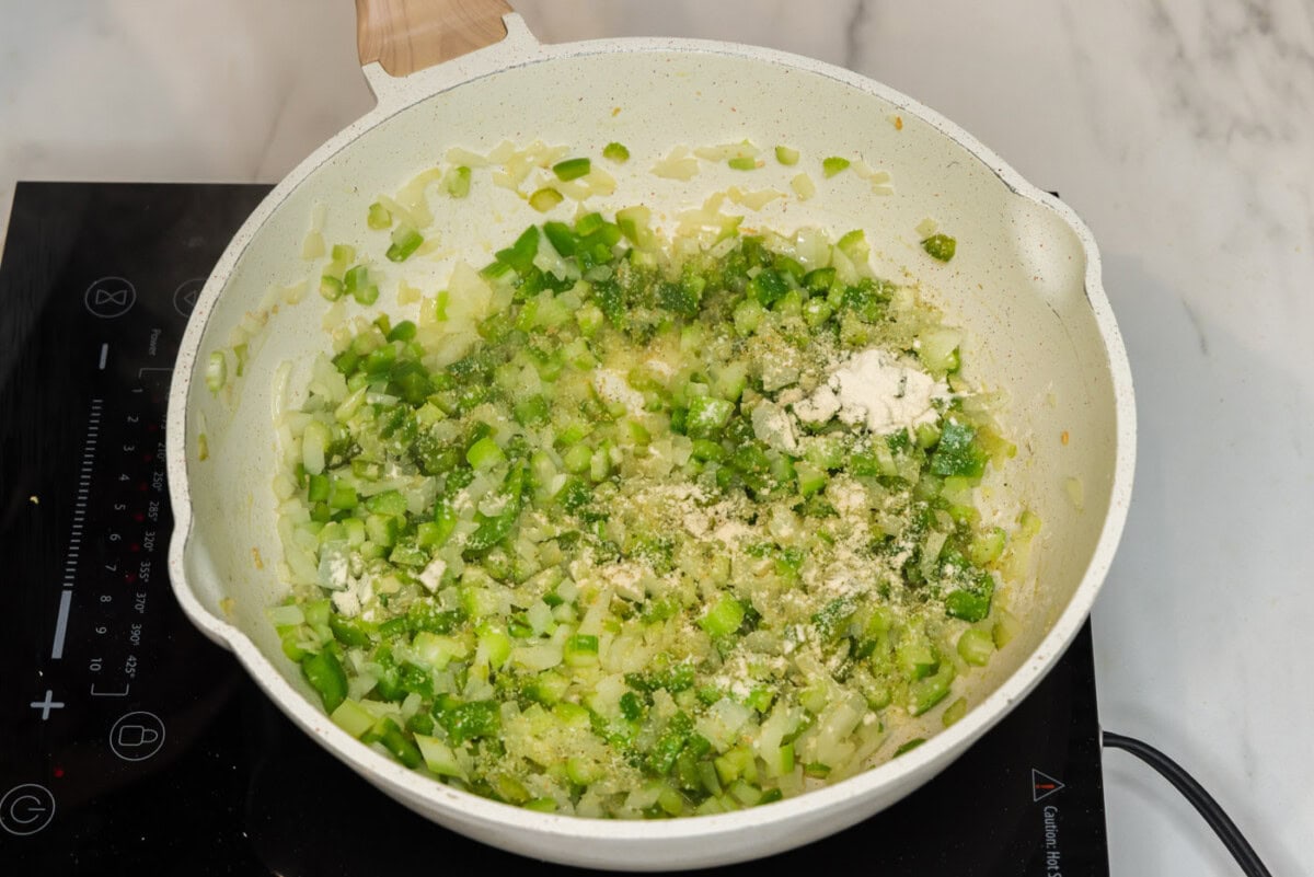 adding seasonings to skillet with celery, onion, and bell peppers
