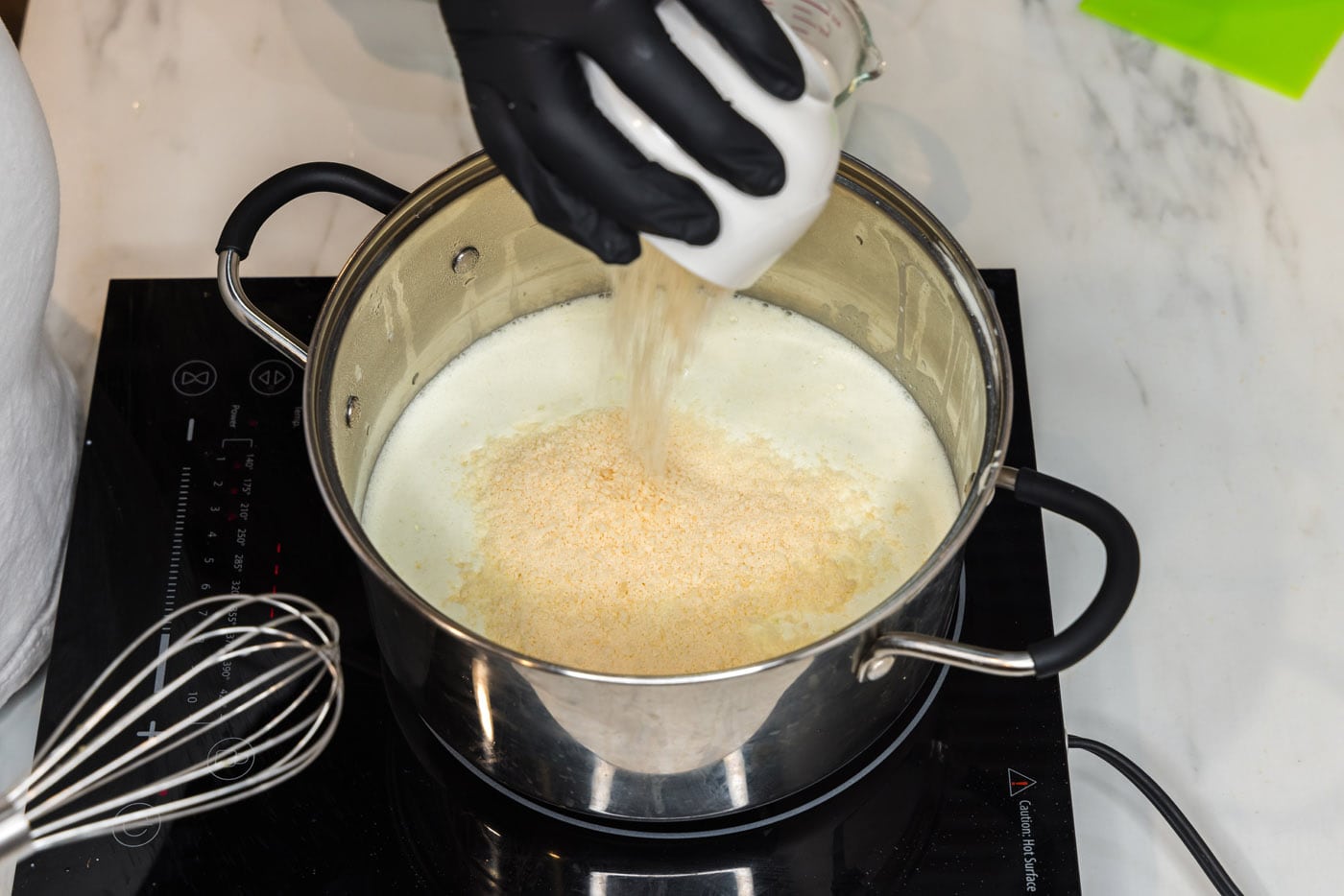pouring parmesan cheese into pasta sauce in a pot