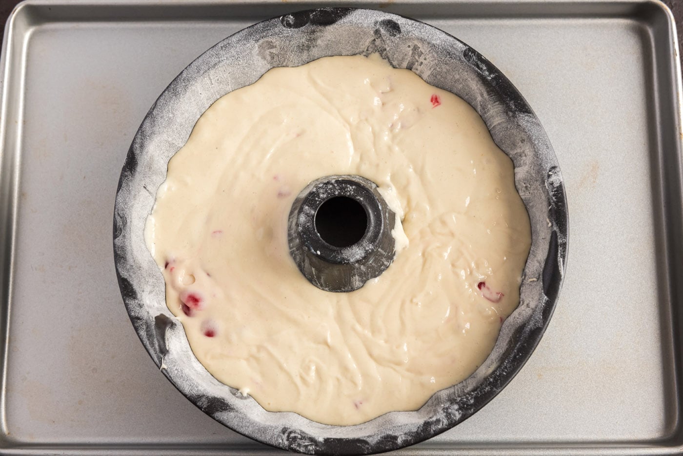 cake batter with cherries added to bundt pan