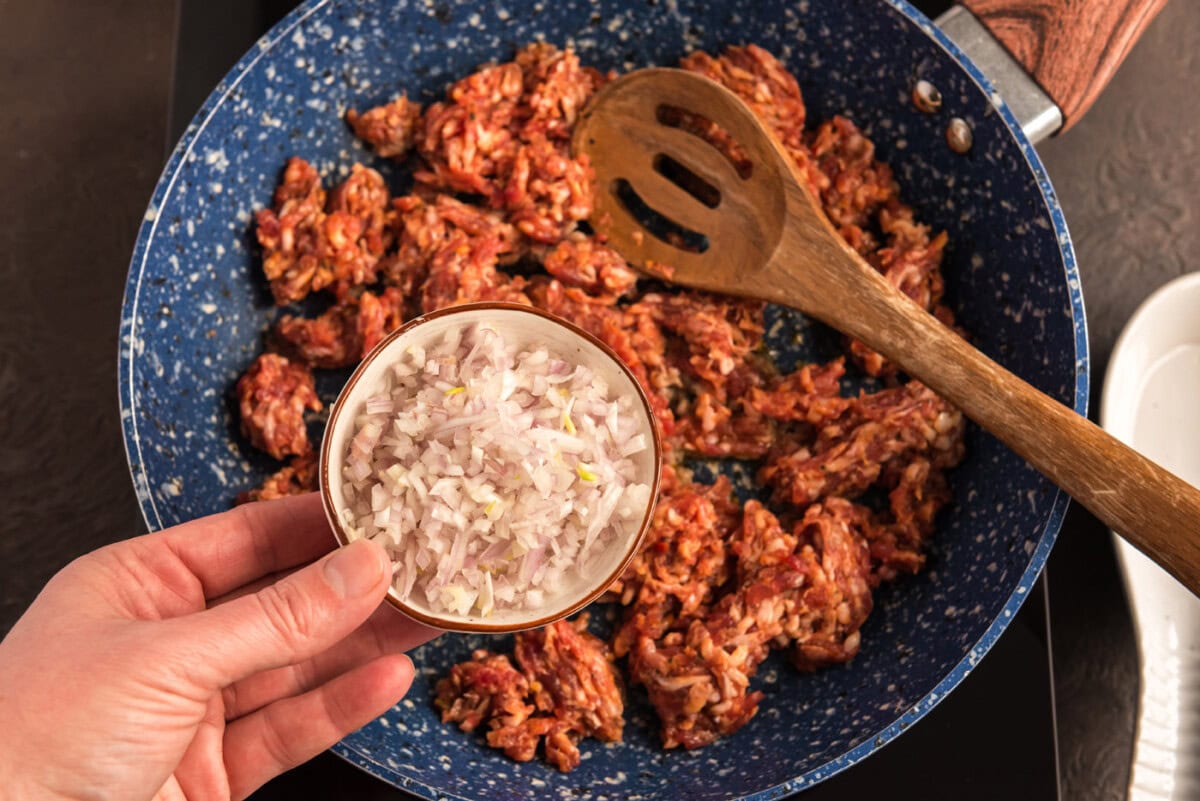 adding shallots to pan with ground pork sausage and garlic