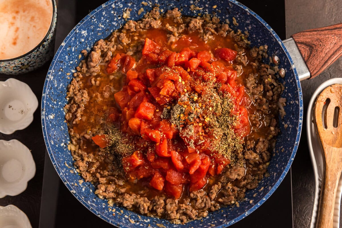 diced tomatoes and seasonings added to ground sausage in skillet