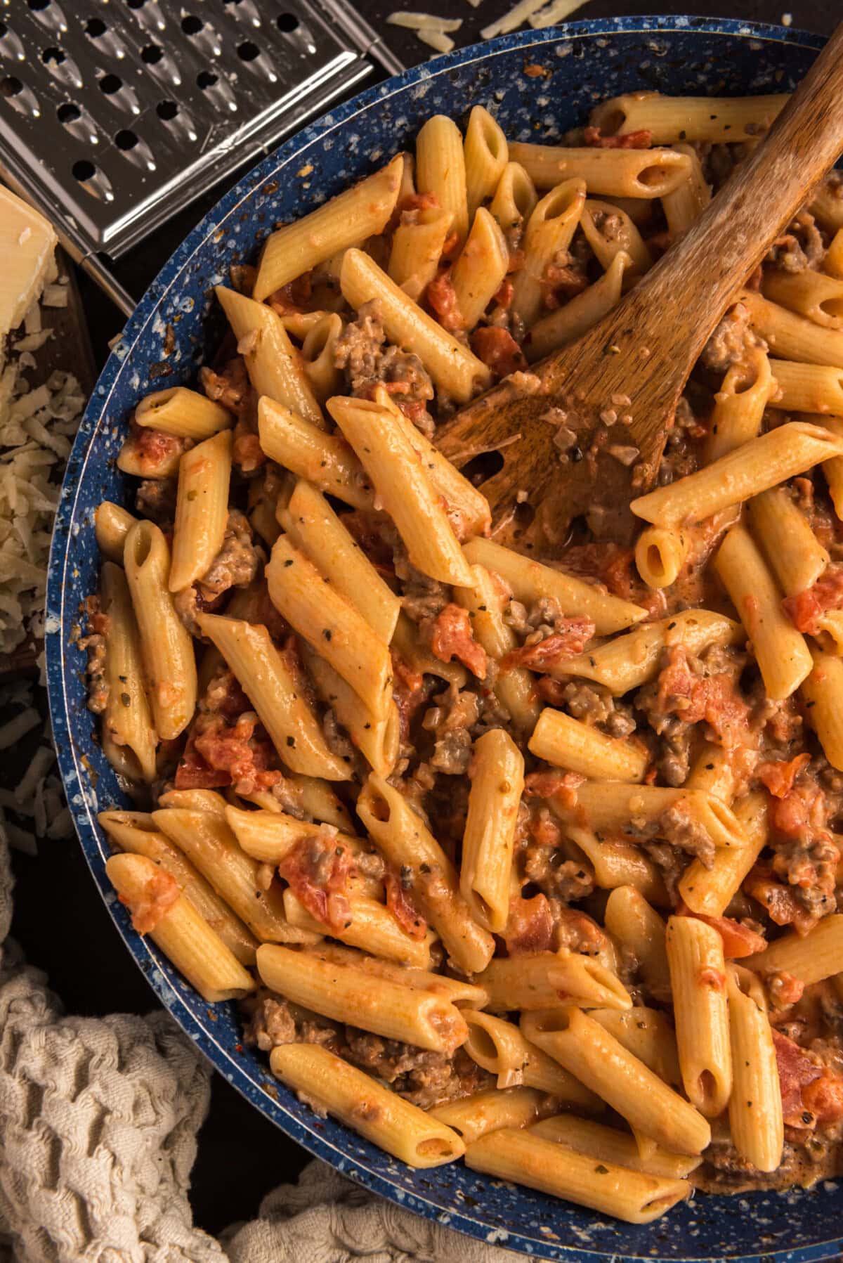 Close up photo of Penne with Tomato Sage Sausage Sauce in a skillet with a spoon