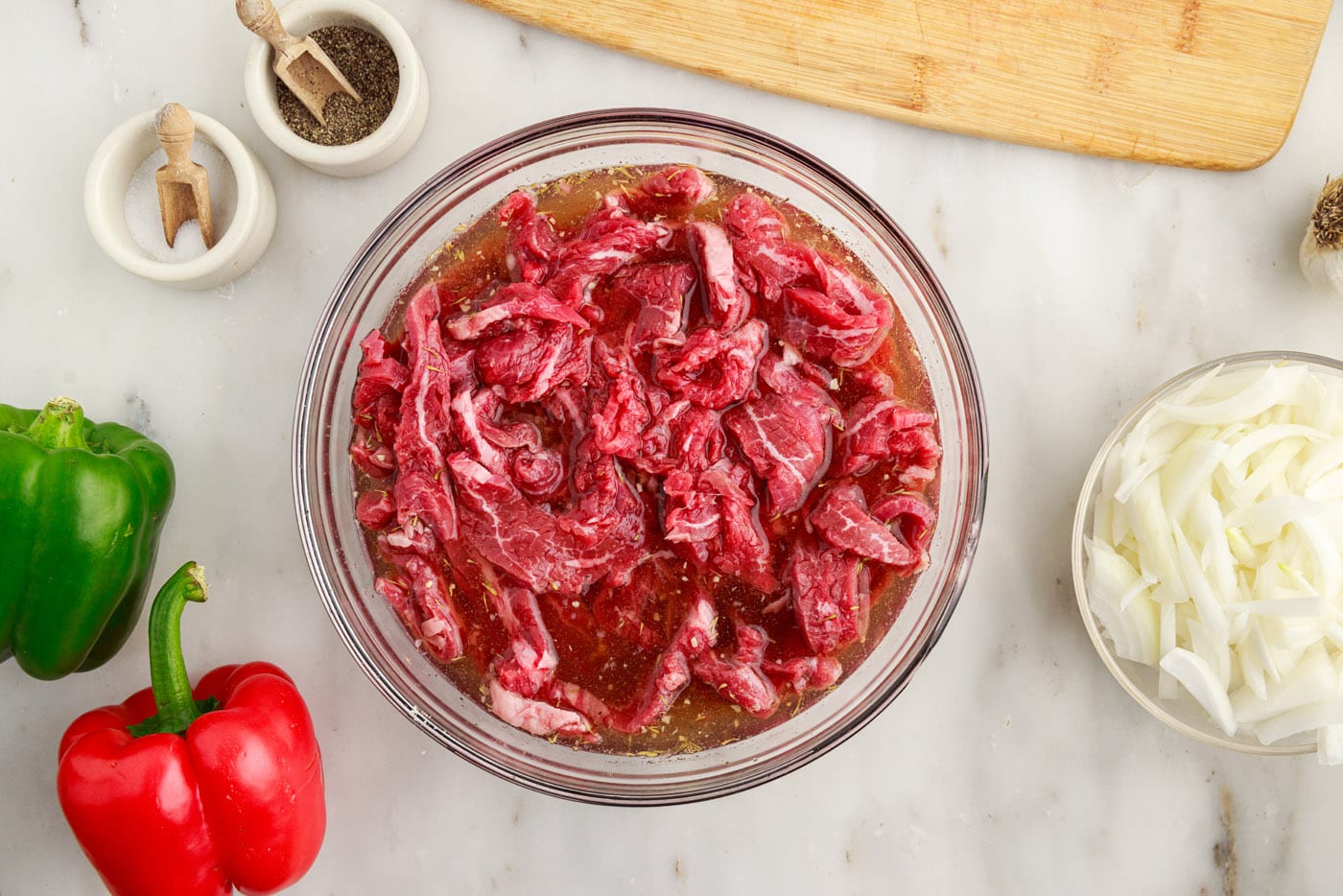 sliced flank steak in a bowl with marinade