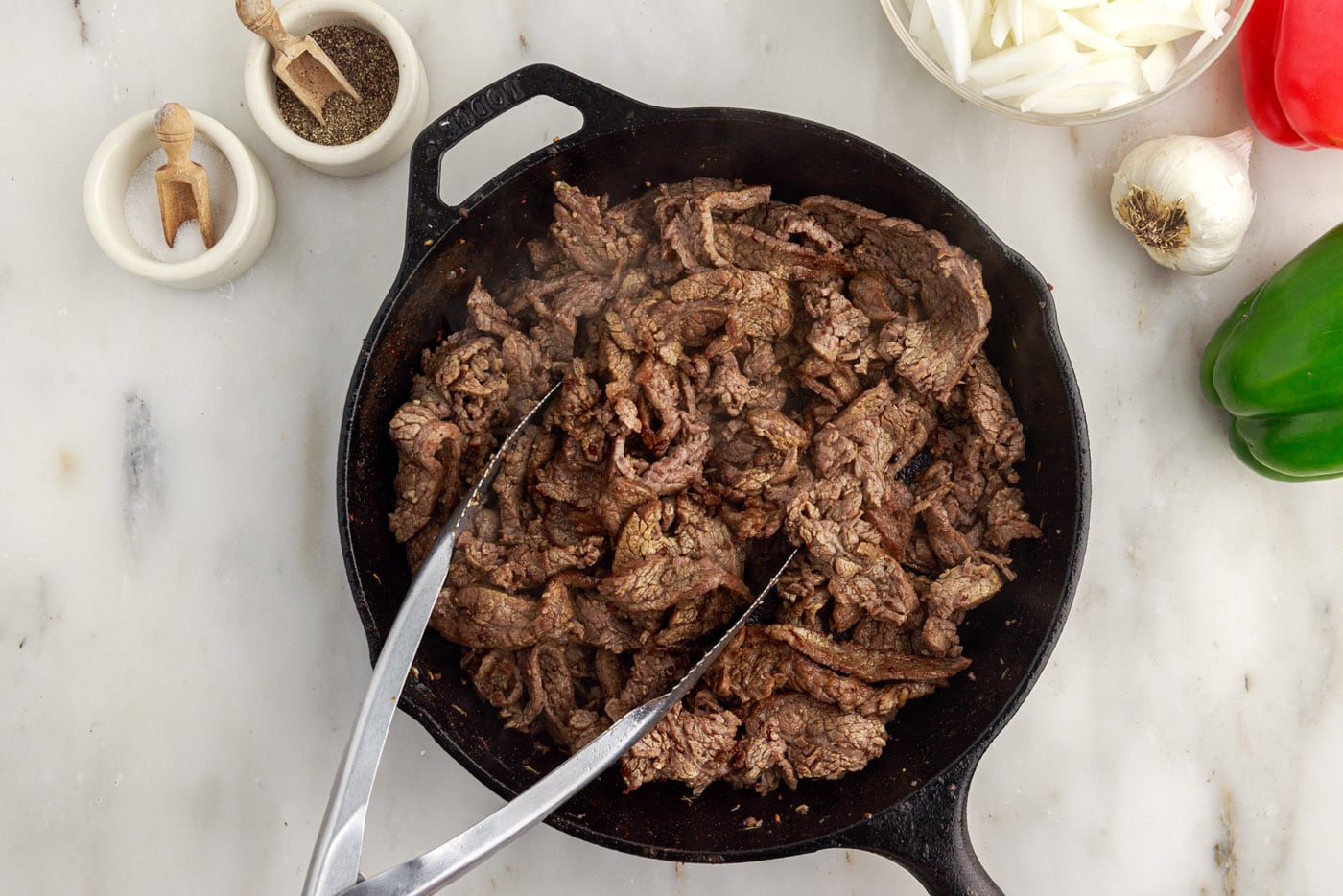 cooked flank steak slices in a cast iron skillet