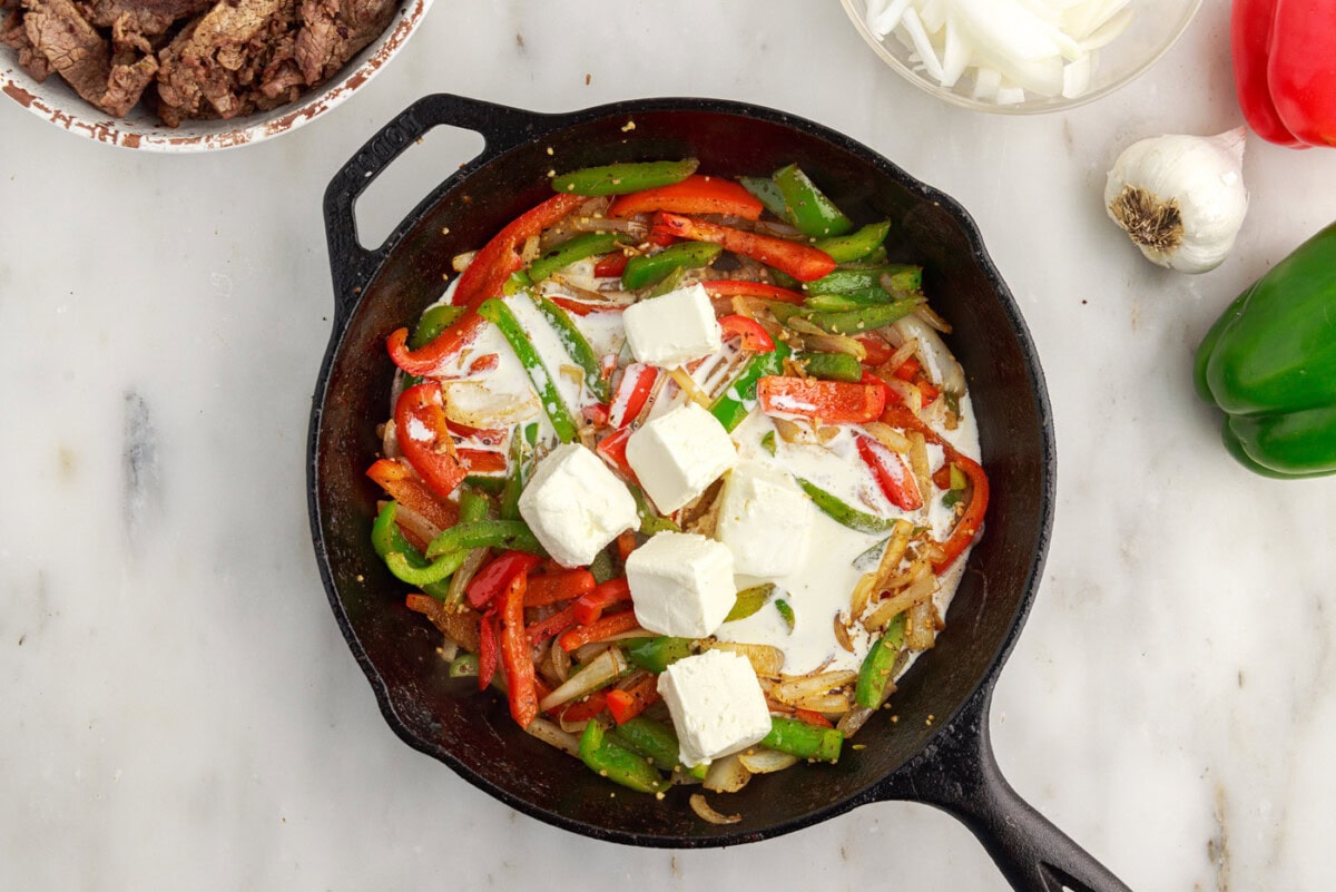 cream cheese and heavy cream added to skillet with bell peppers and onions