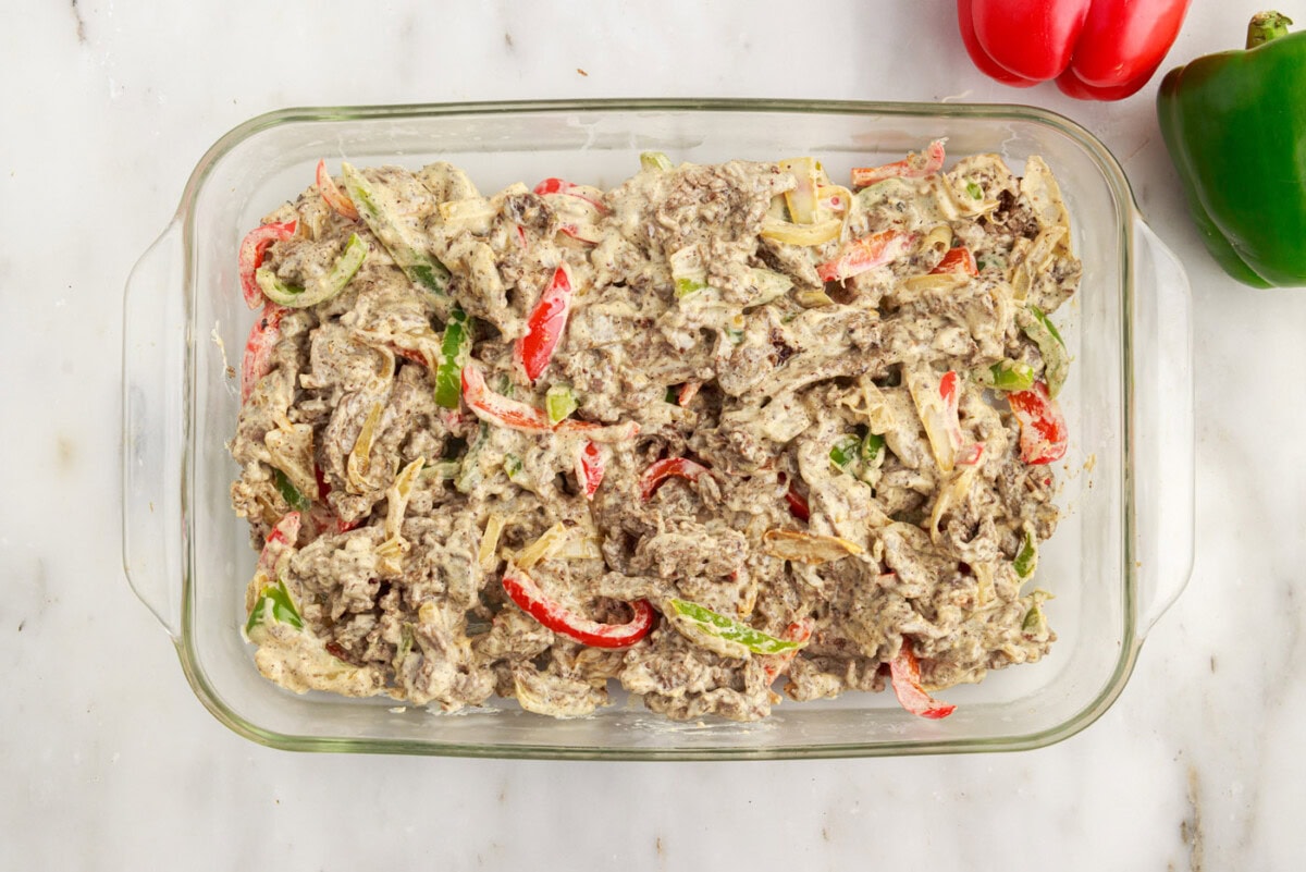 philly cheesesteak casserole ingredients in a baking dish
