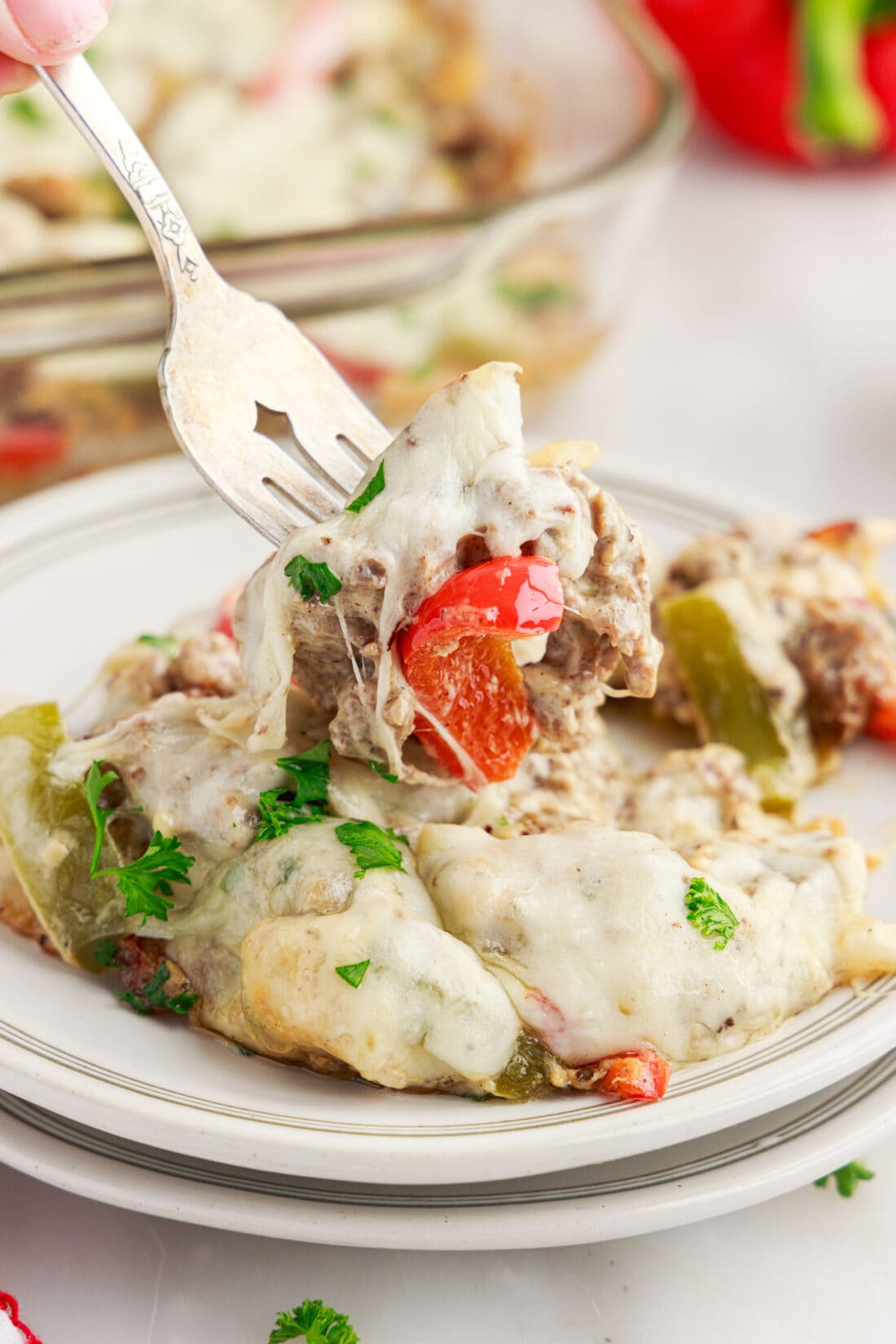 Forkful of Philly Cheesesteak Casserole being lifted off a plate of Philly Cheesesteak Casserole