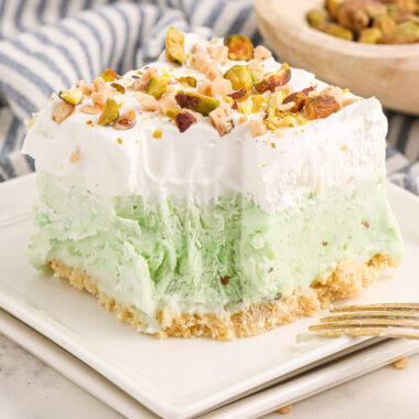 Close up photo of a square of Pistachio Ice Cream Cake on a plate with a bite removed