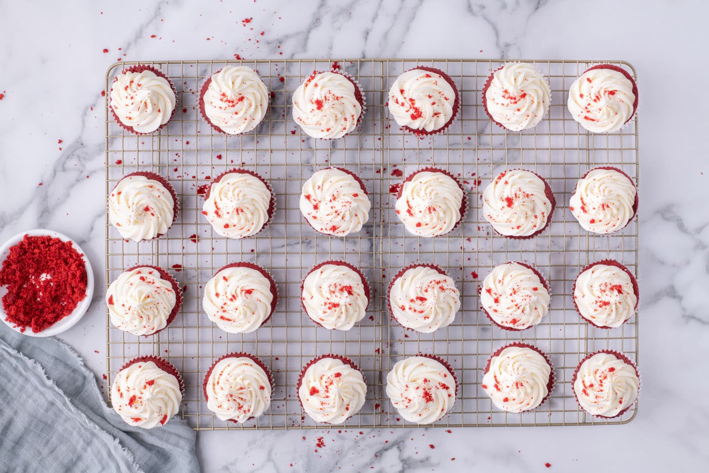 overhead of red velvet cupcakes with cream cheese frosting on a wire cooling rack