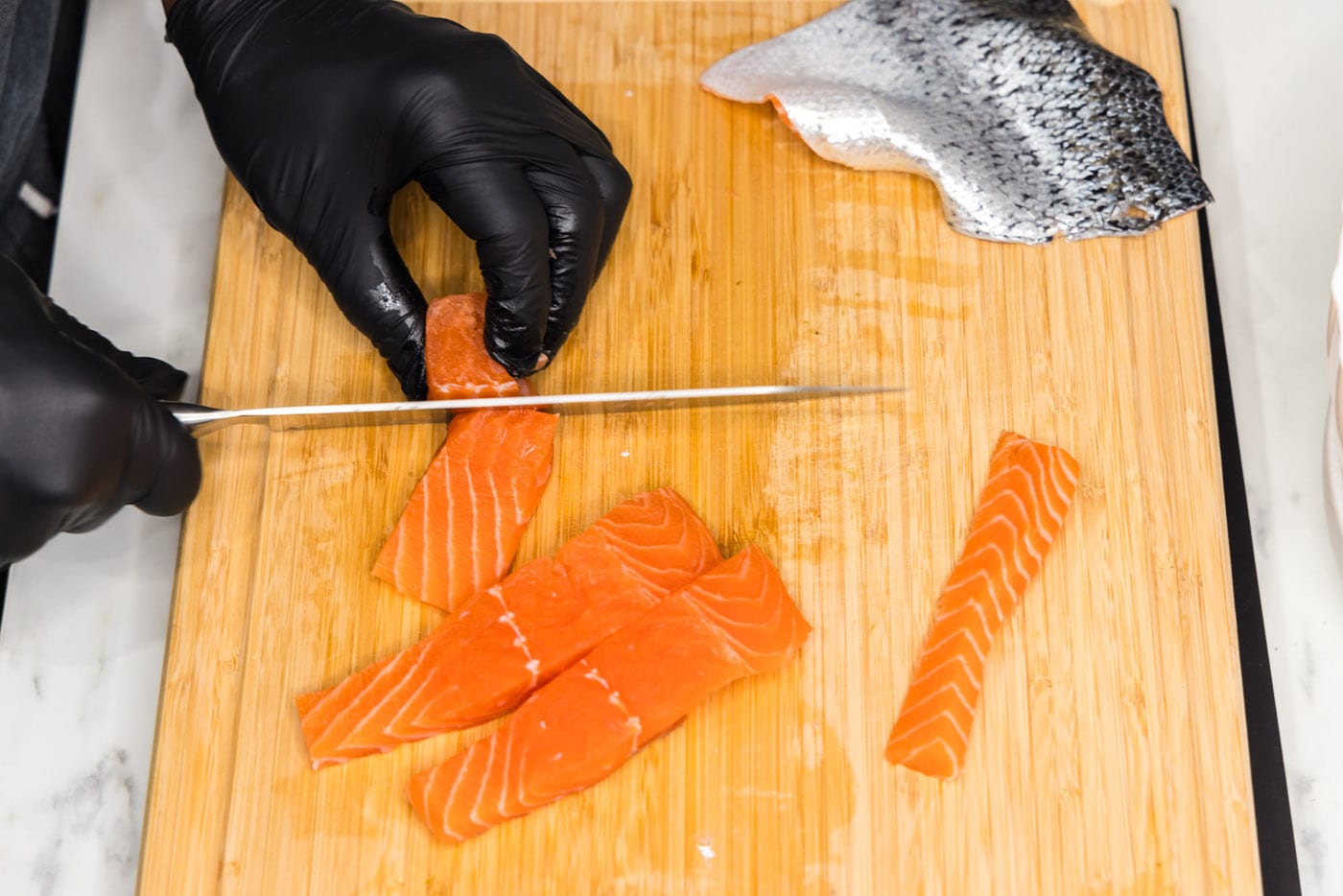 slicing salmon filet into cubes