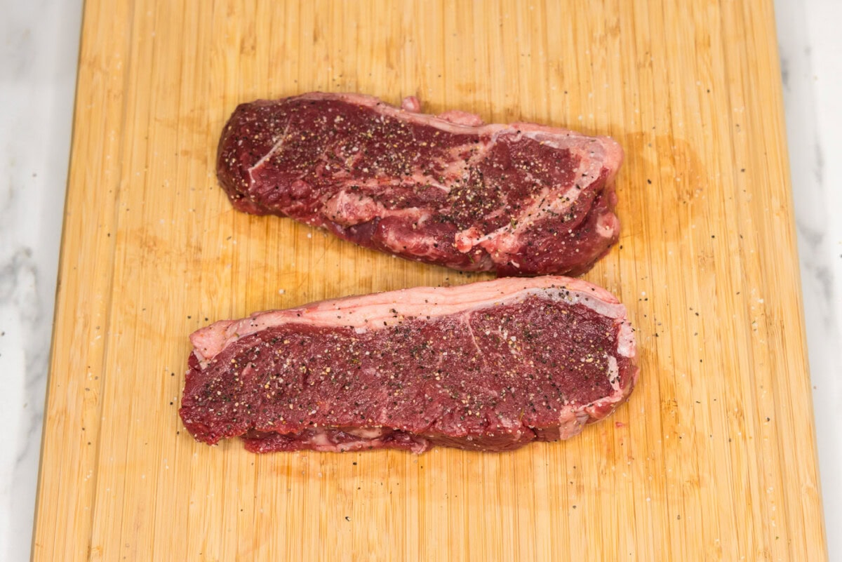 seasoned new york strip steaks on a cutting board