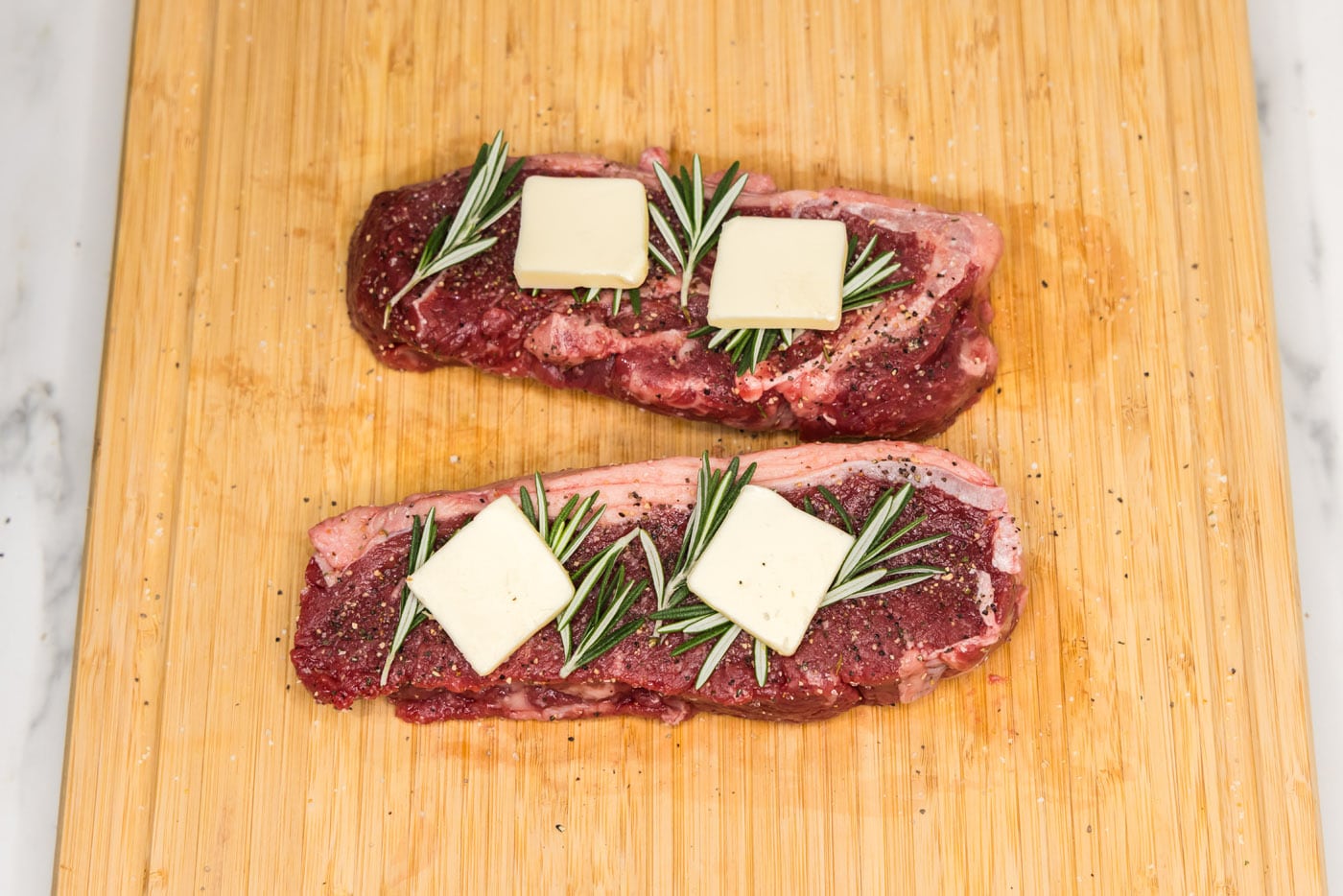 New York strip steaks with fresh rosemary and butter