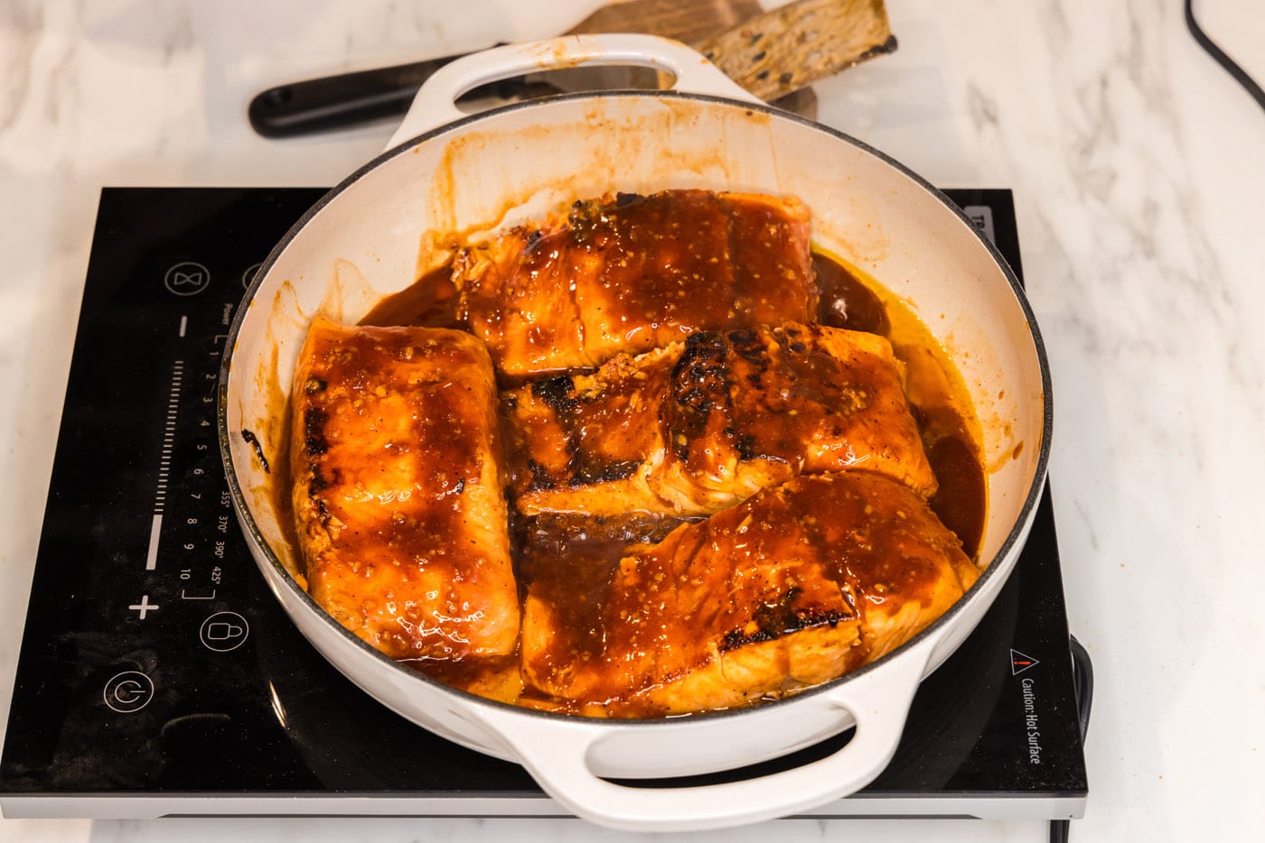 baked salmon filets in a skillet with spicy marinde