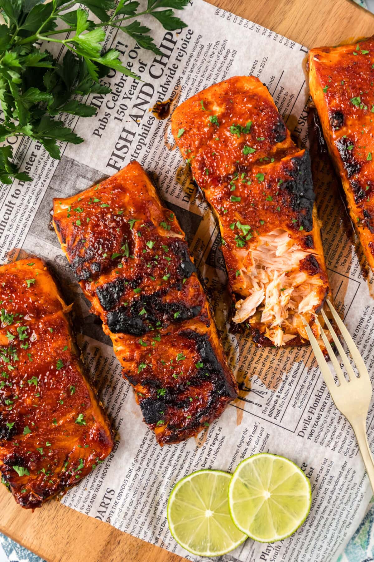 Spicy Salmon filets on parchment with one filet broken up with a fork