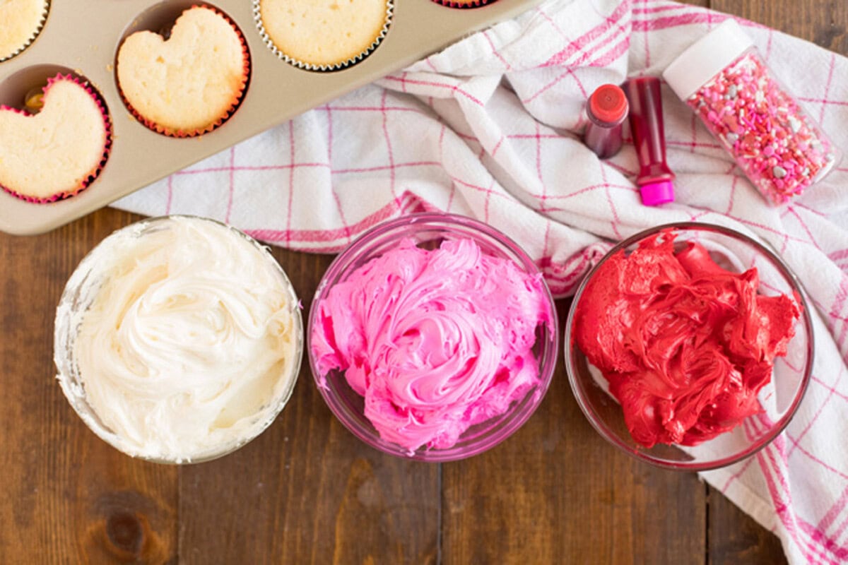 Three bowls of white, pink and red frosting