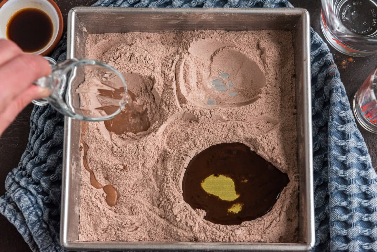 pouring vinegar into well of wacky cake