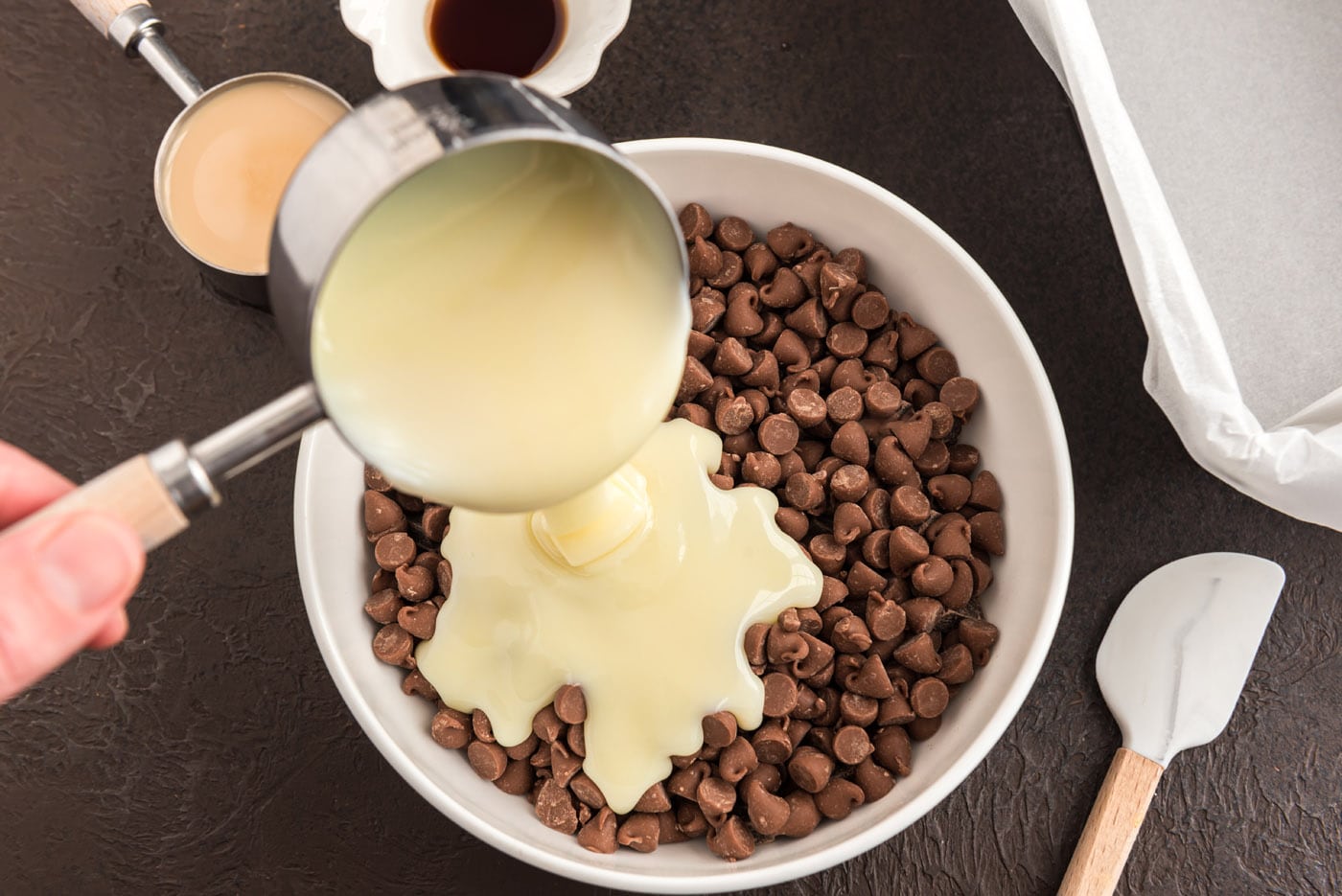 pouring sweetened condensed milk over chocolate chips