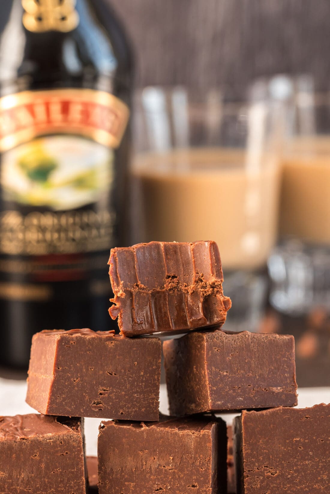 Close up photo of a stack of 4 Ingredient Baileys Fudge with a bite taken out of the top square