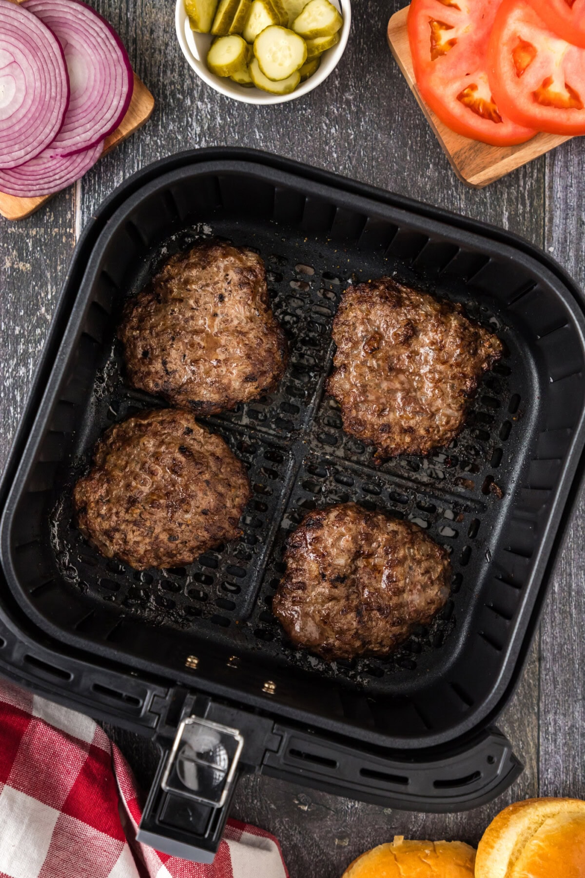 Four Air Fryer Burgers in an air fryer basket