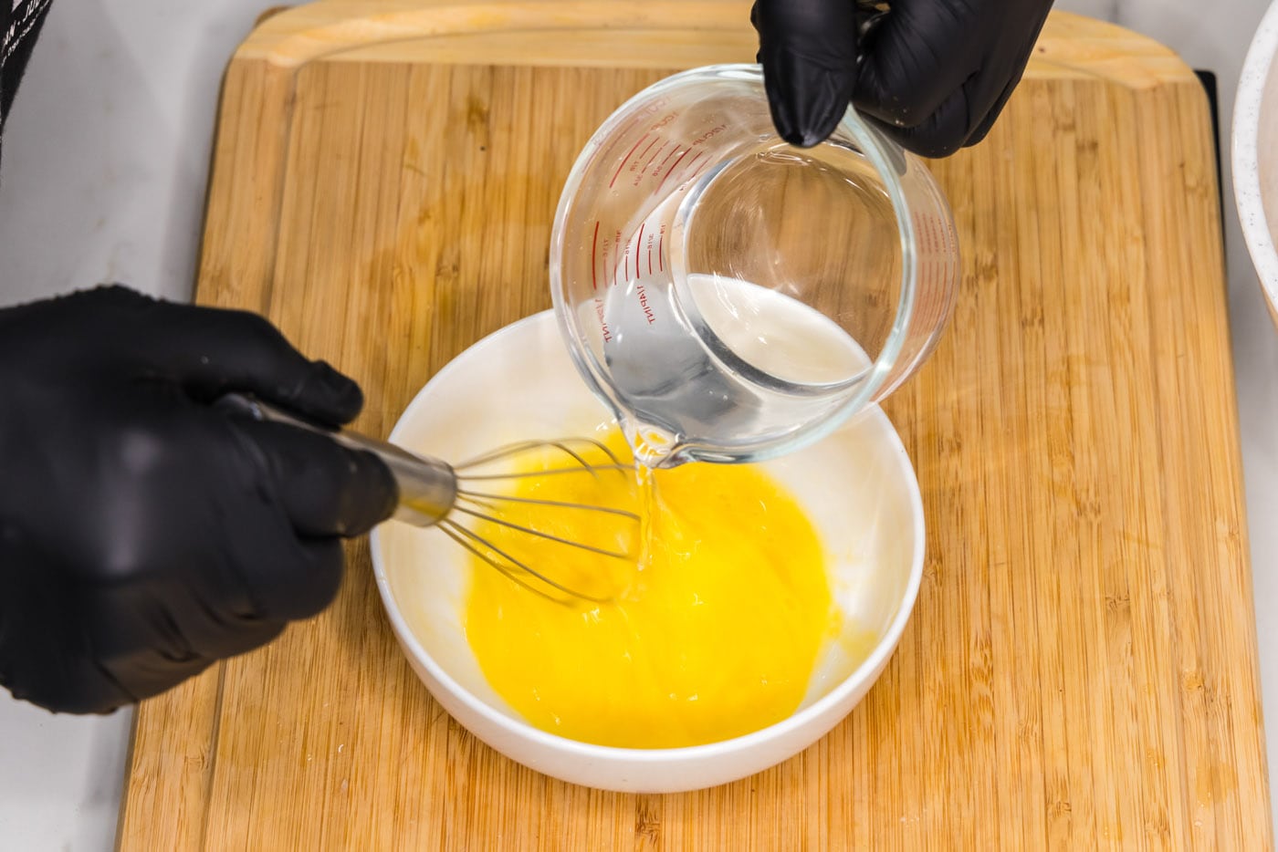whisking egg with water in a bowl