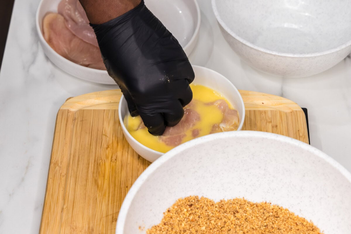 dipping chicken breast into egg