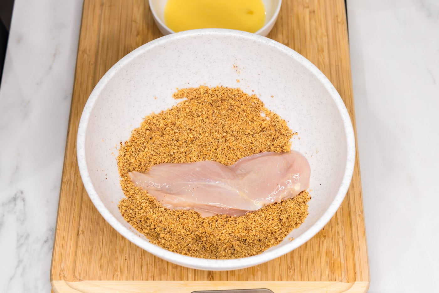 dredging chicken breast in crushed almonds