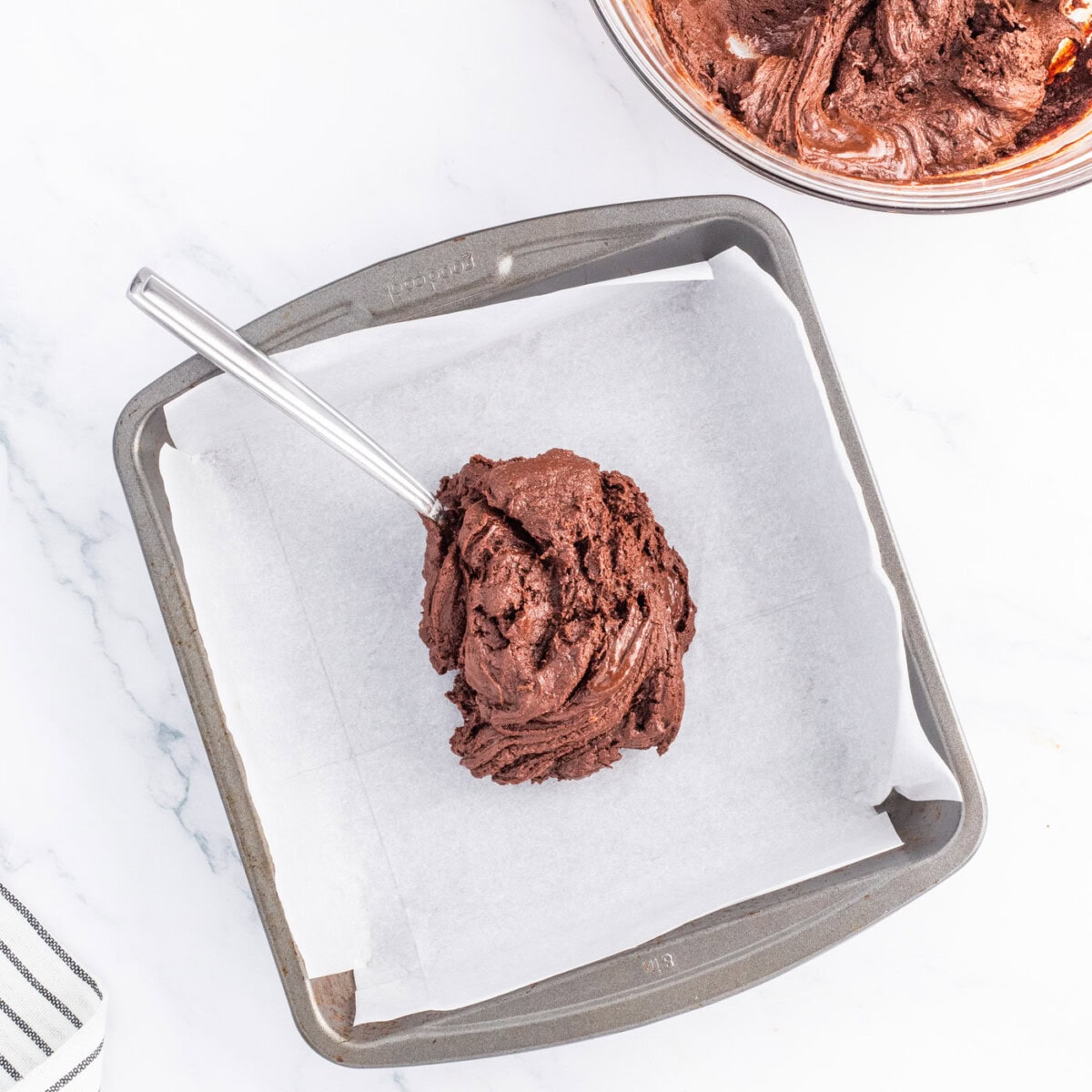 spreading chocolate fudge mixture in a baking pan