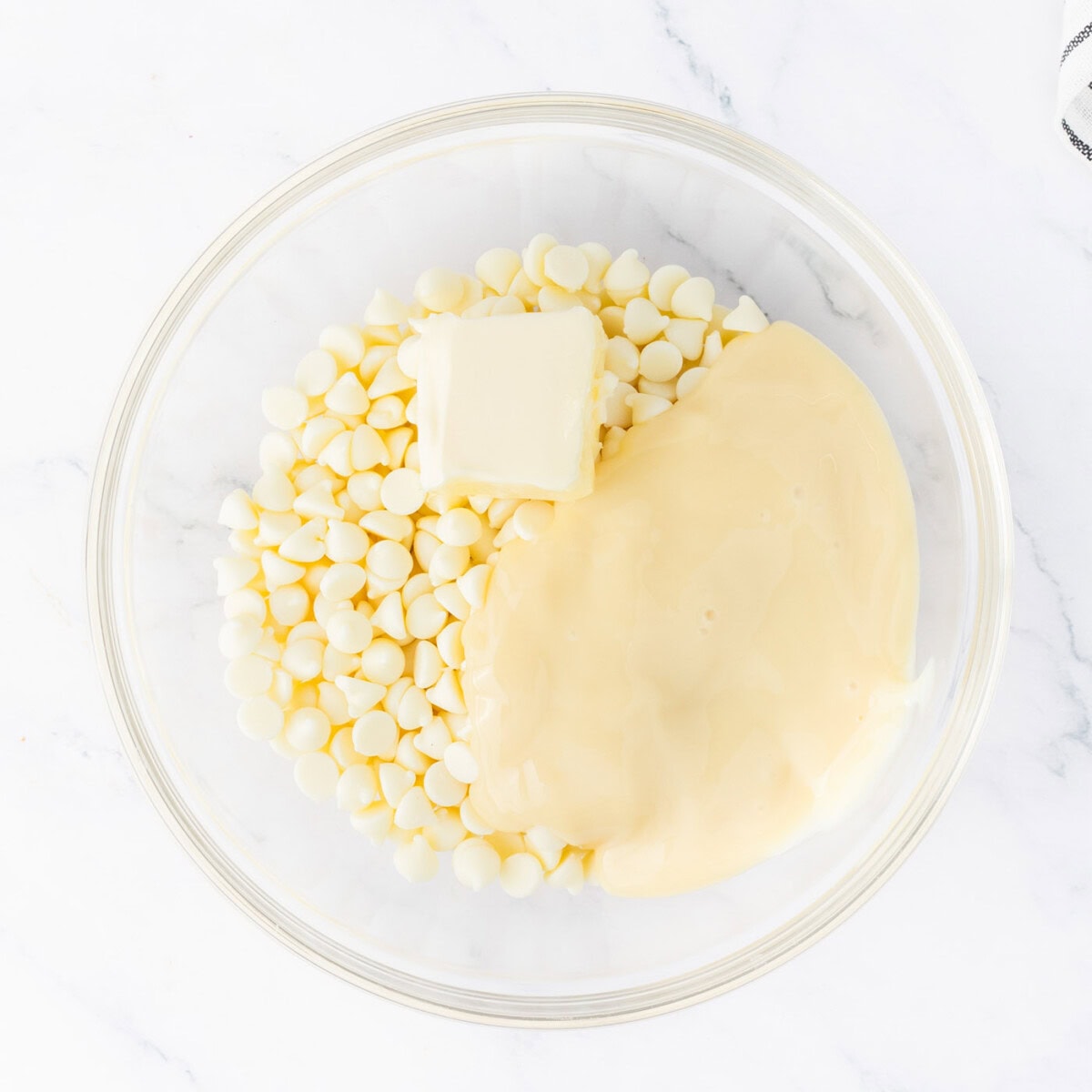 white chocolate chips in a bowl with sweetened condensed milk and butter