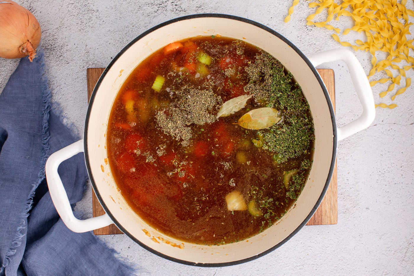 beef broth and seasonings added to veggie mix in a dutch oven