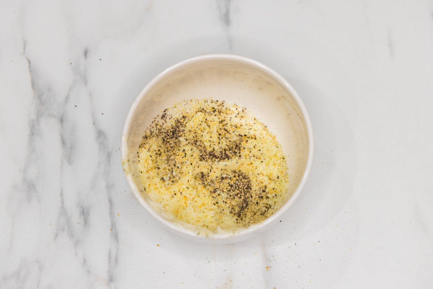 mixing softened butter with garlic salt and pepper in a bowl