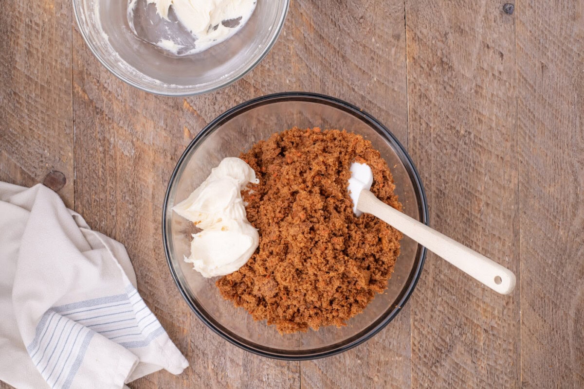 combining cream cheese frosting with crumbled carrot cake
