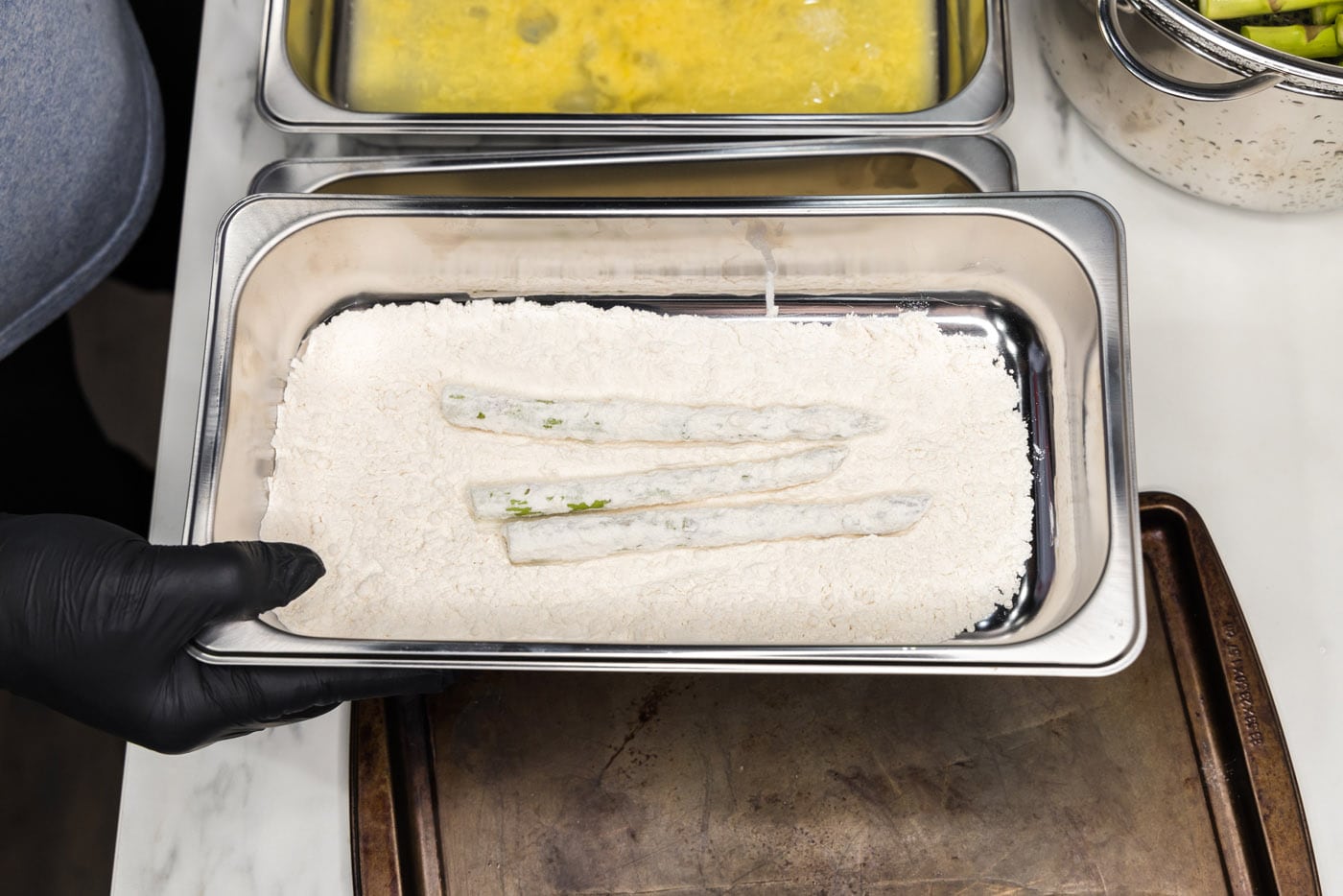 dipping asparagus spears into flour