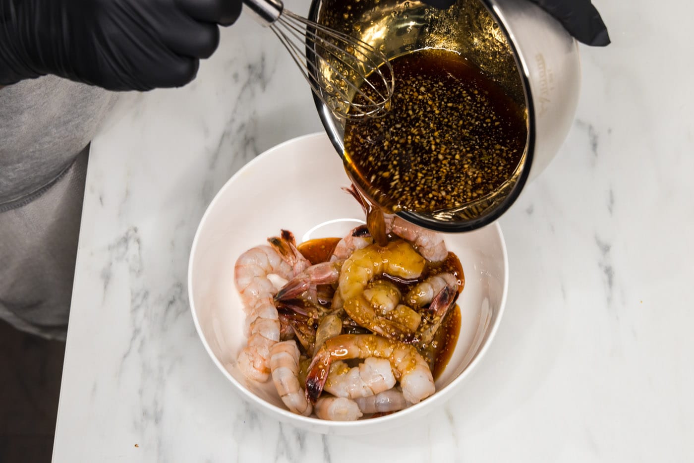 pouring honey garlic sauce over shrimp in a bowl