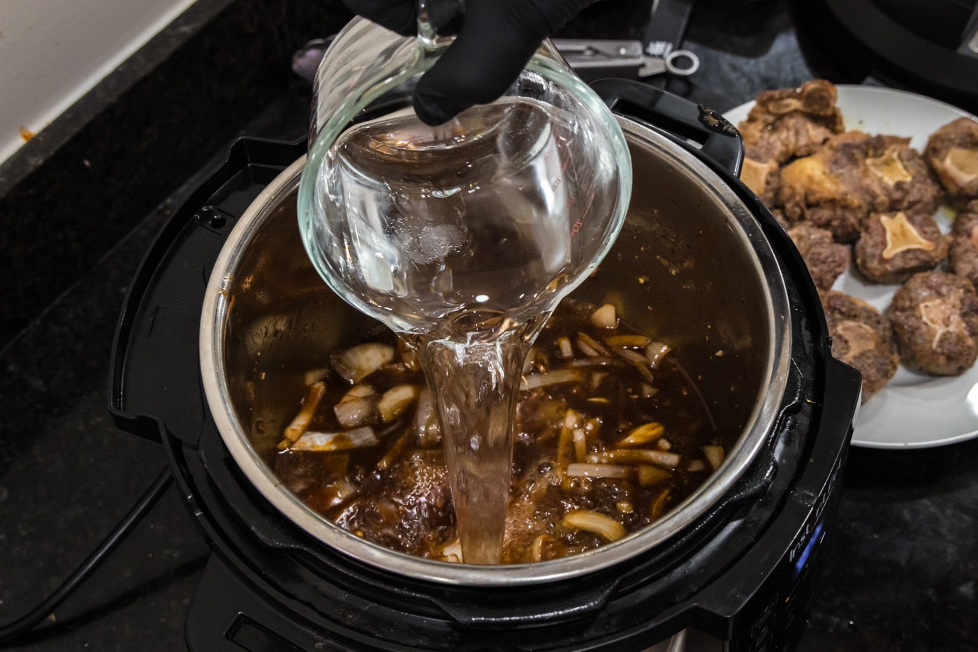 pouring water into instant pot oxtail stew