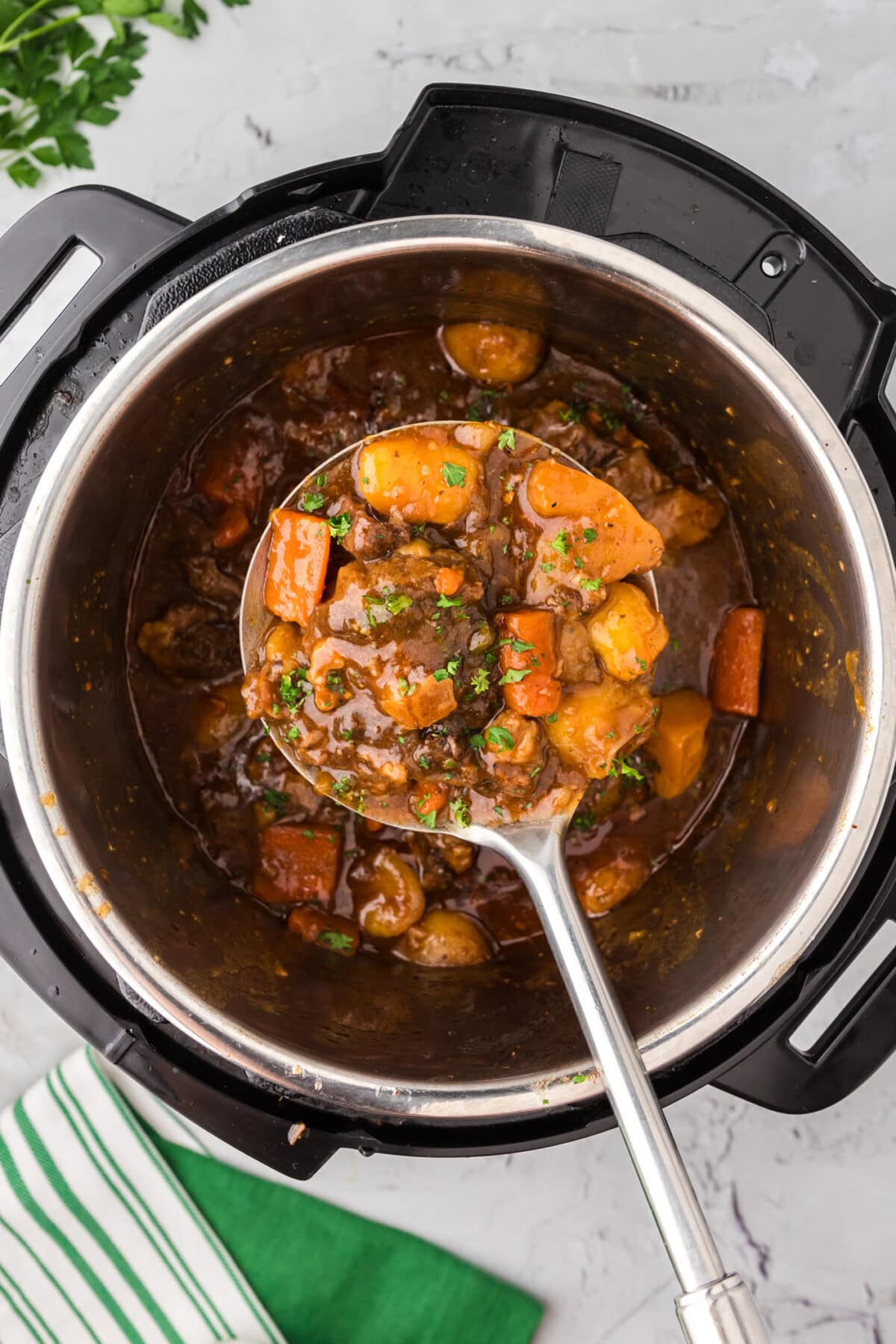 Serving spoon holding Instant Pot Oxtail over an Instant Pot