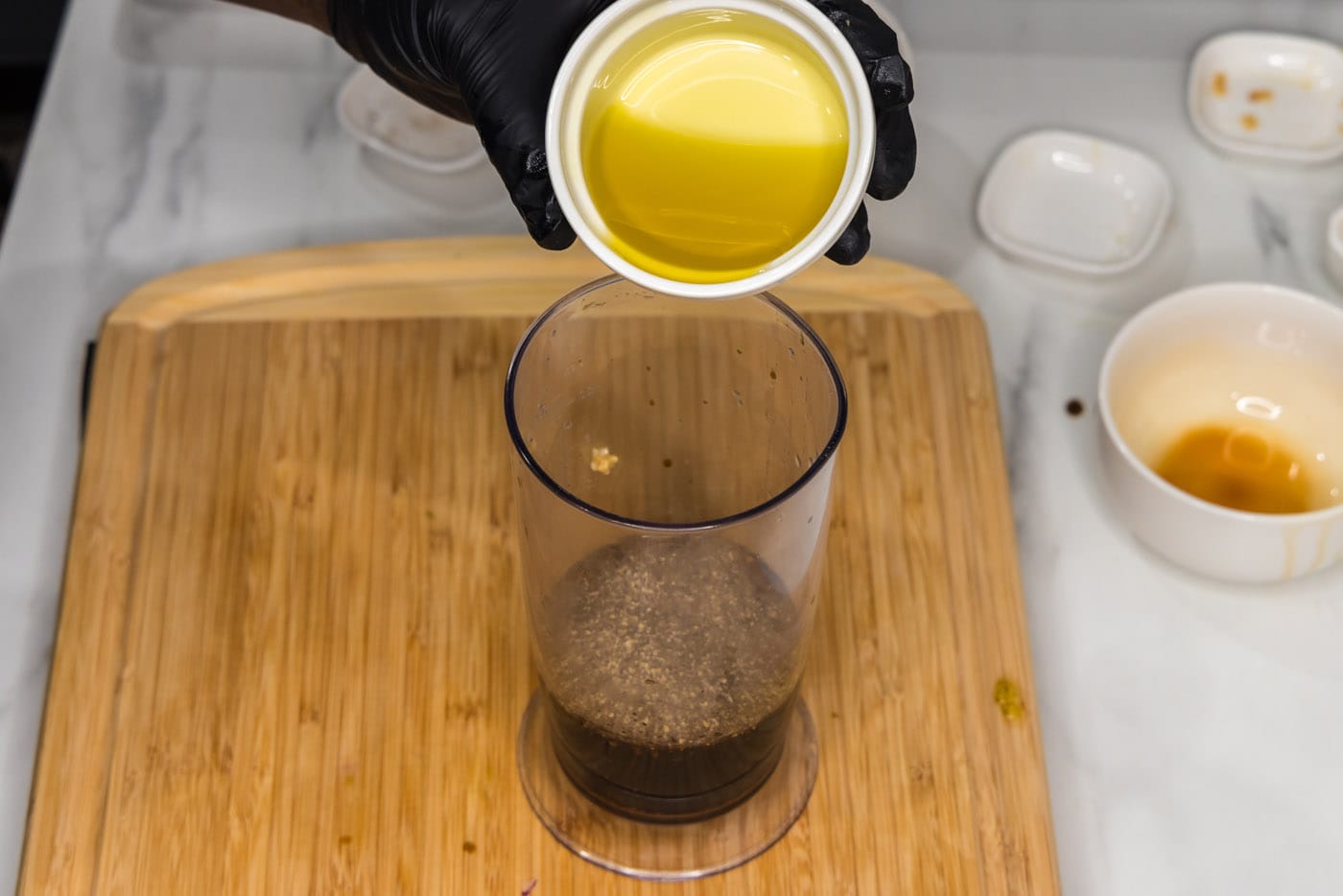 pouring olive oil into marinade in an immersion blender